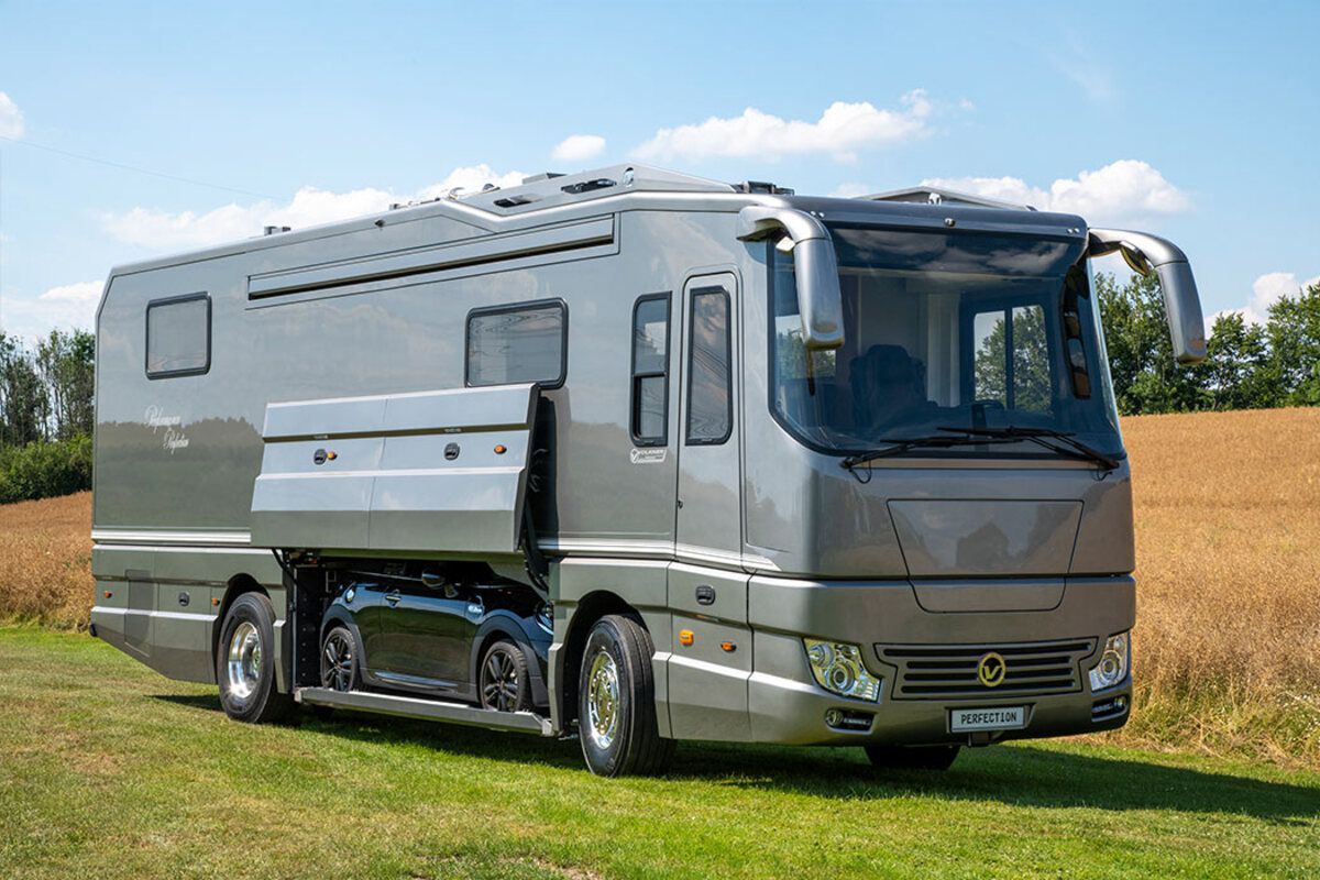 Exterior of Volkner Mobil Performance Perfection, car in compartment with door opened, on a grassy lawn, with a grain field and a light blue sky in the background