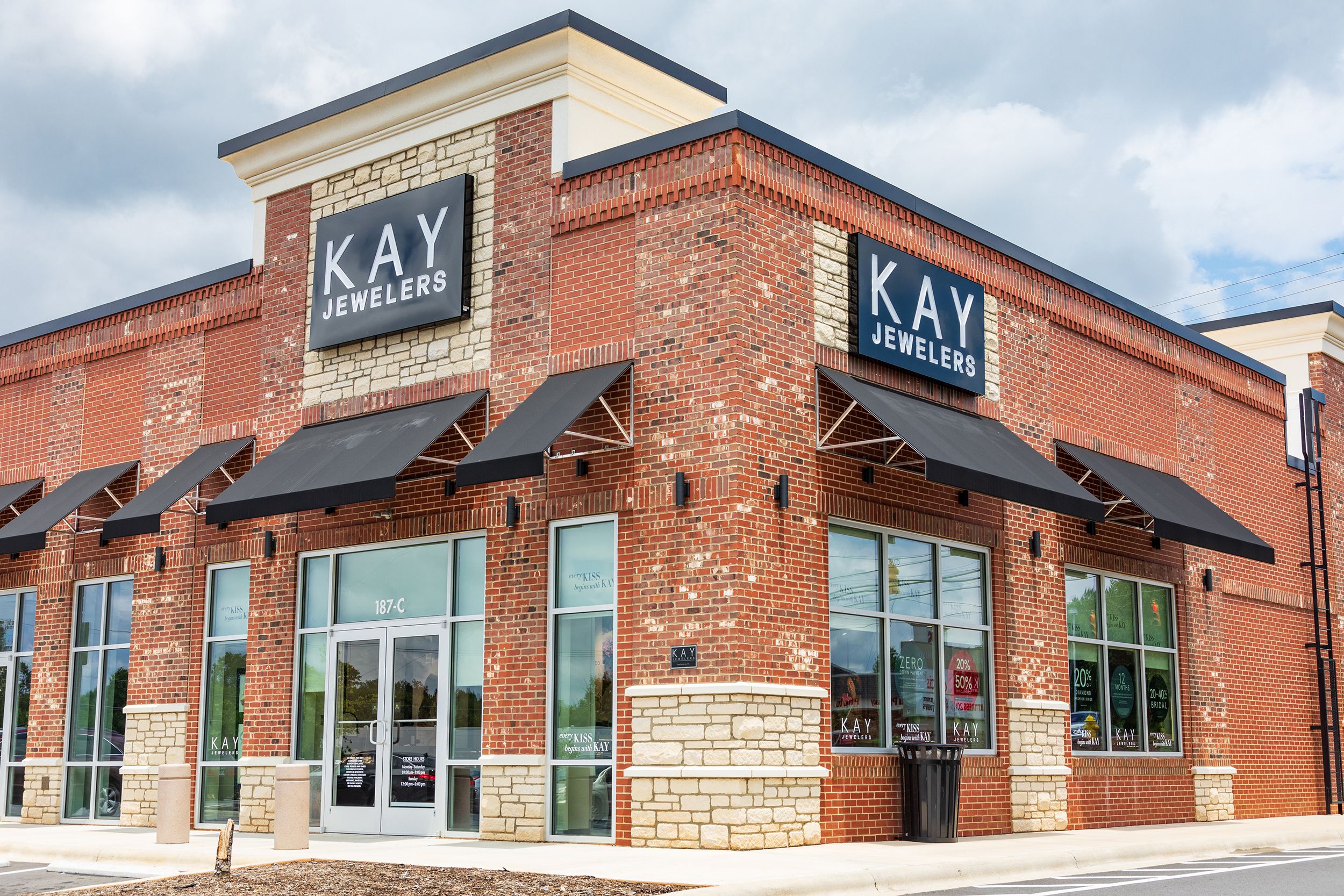 Front exterior of Kay Jewelers retail store, Statesville, North Carolina, brick building with sidewalk, grey and white clouds in the background