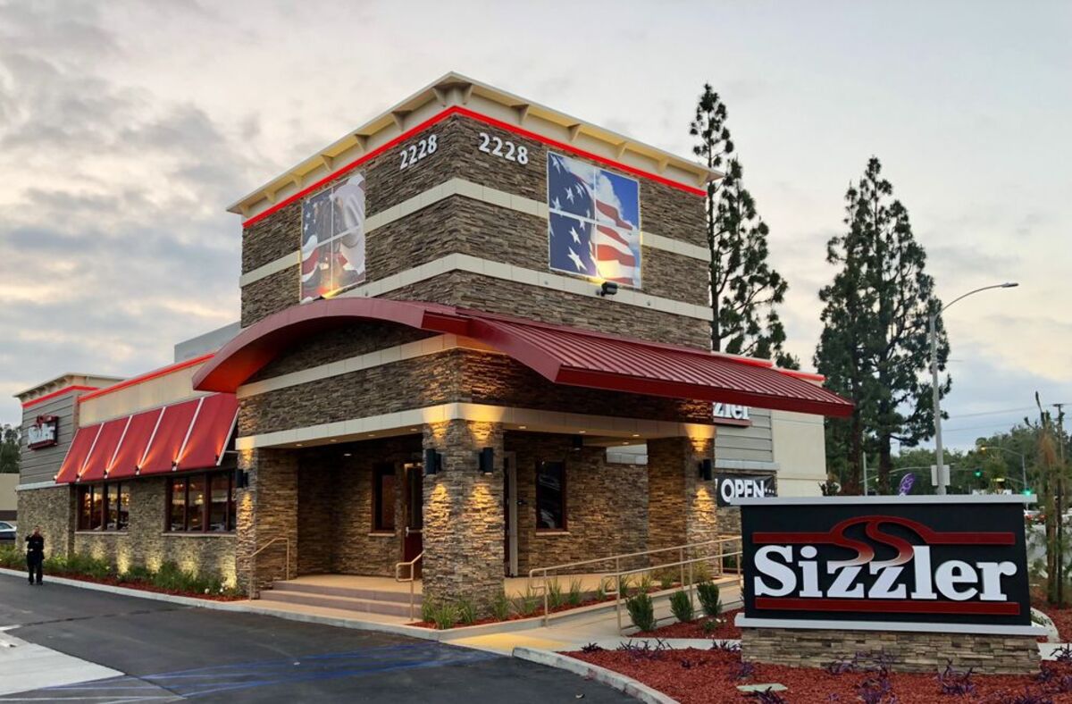 Front and side exterior of Sizzler, Ontario, California, during sunset with a dramatic sky in the background