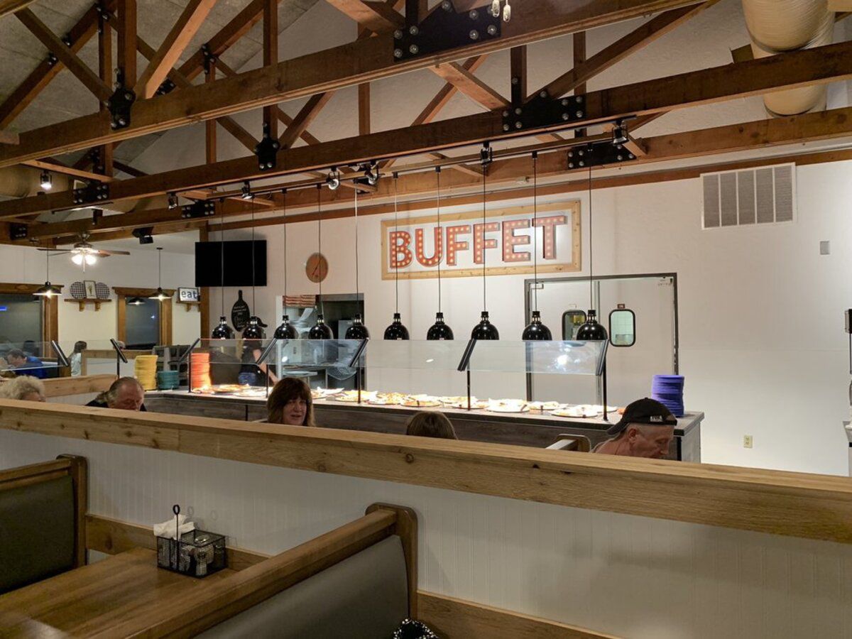 Interior pizza buffet area with different pizzas, Pizza Inn, Jackson, Missouri, two rows of seating with people seated and eating, clean and well-lit