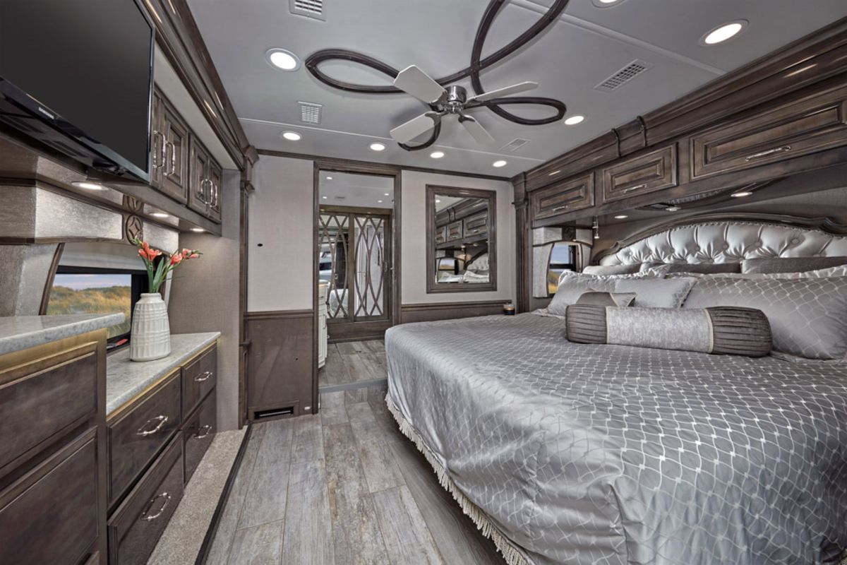 Interior of Entegra Cornerstone, bedroom with a large bed and grey-brown wooden cabinets