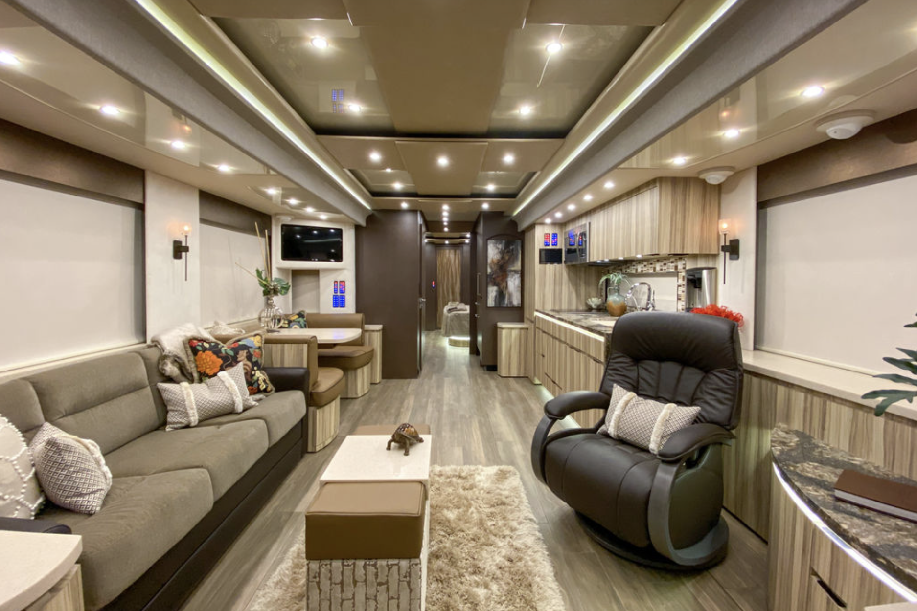 Interior of Newell Coach p50, seating area and kitchen with lined wooden accents