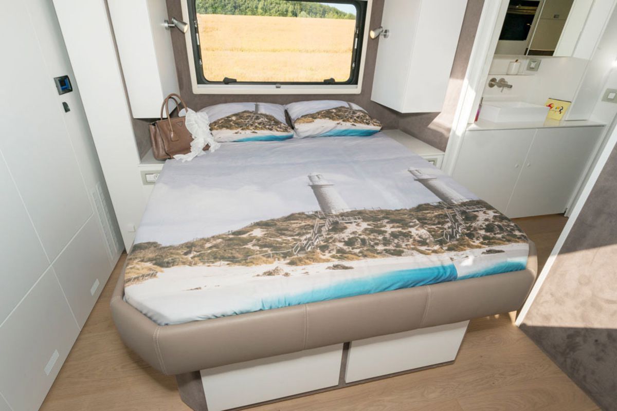 Interior of Volkner Mobil Performance Perfection, bedroom with bed, closet on the left, and bathroom on the right