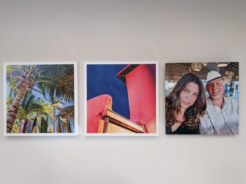 Three square photos on a wall: surfboards and palm trees, a red building against a blue sky, and a smiling couple sitting together indoors.