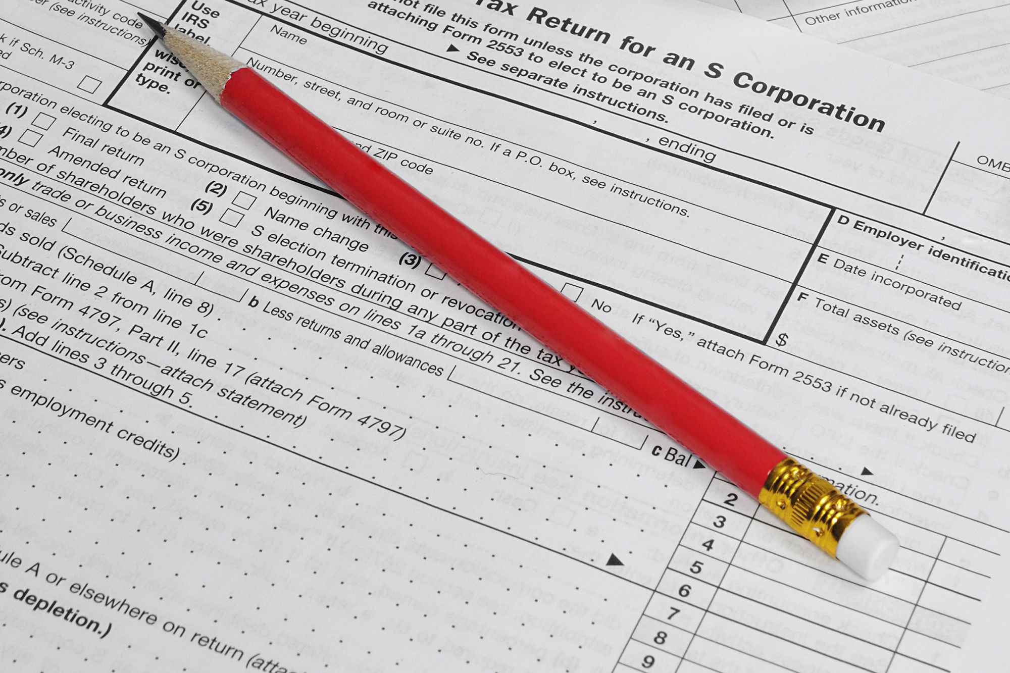 A pencil with red exterior on a paper IRS S corp tax form