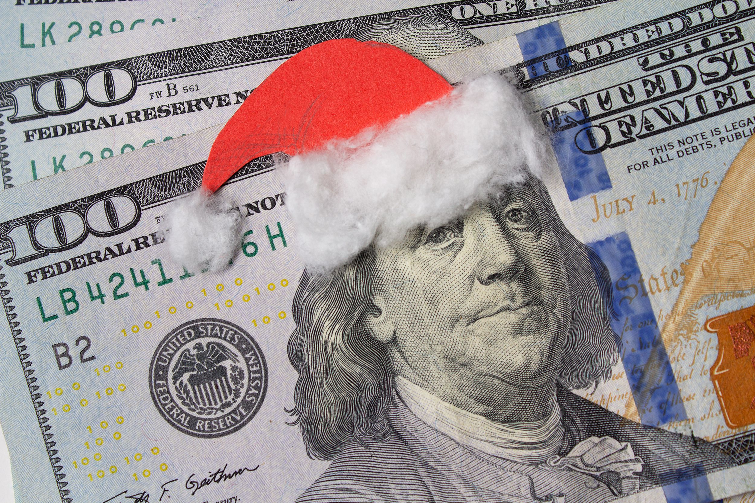 Closeup of santa hat on Benjamin Franklin on a U.S. $100 dollar bill, on two more