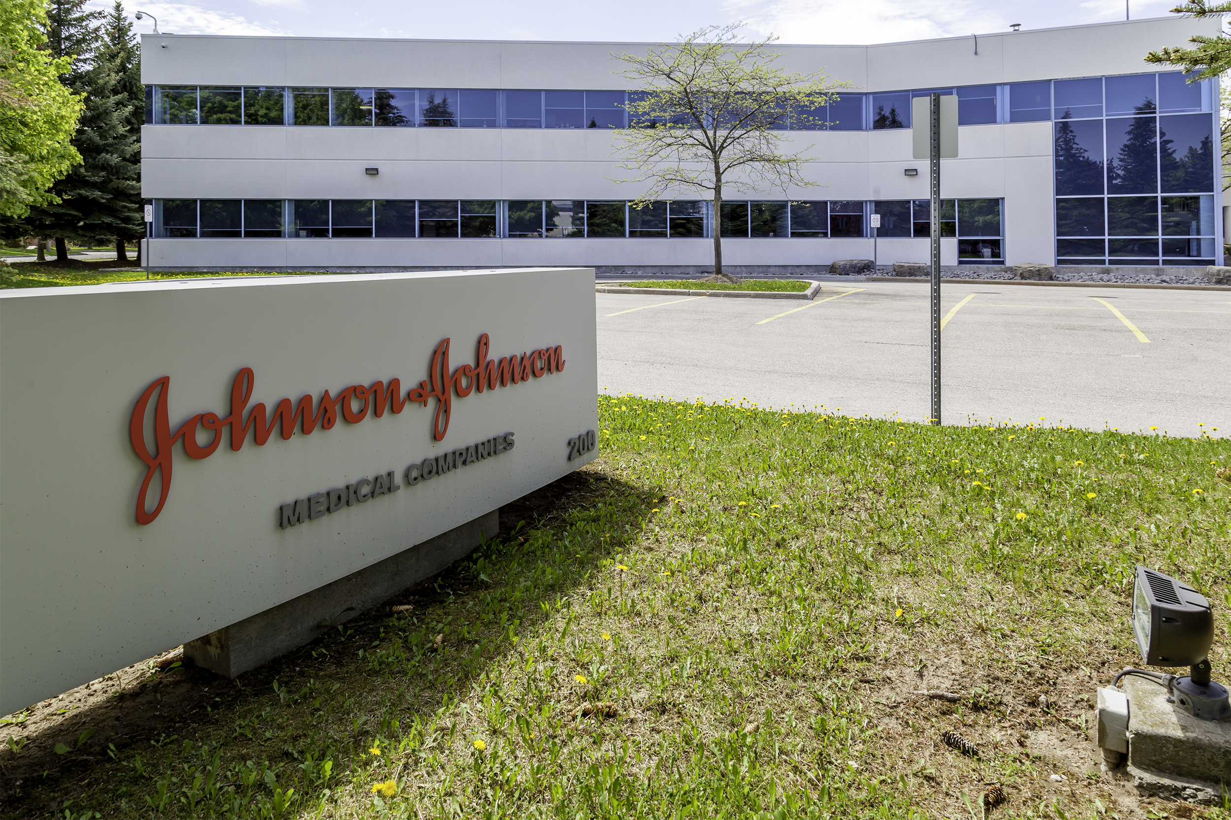 Sign of Johnson & Johnson Medical Products, Markham, Ontario on the left foreground with the building in the background, empty parking lot in between, on a sunny day during early spring