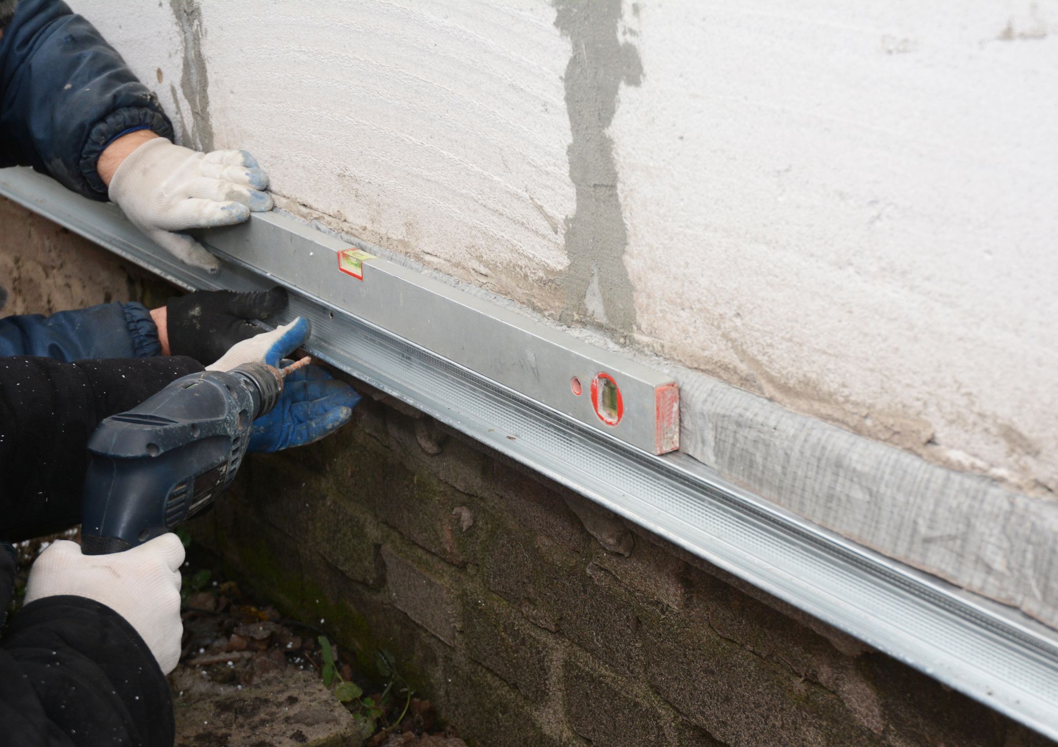 Old house foundation wall repair and renovation with installing metal sheets for waterproofing and protect from rain. Contractors with Foundation repair.