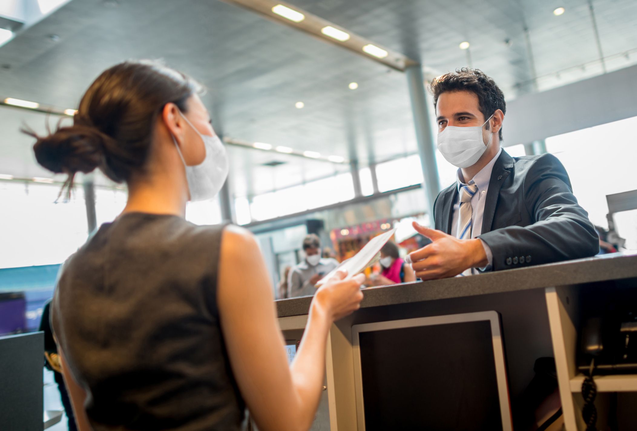 Portrait of a traveling business man doing the check-in at the airport wearing a facemask during the COVID-19 pandemic â travel concepts