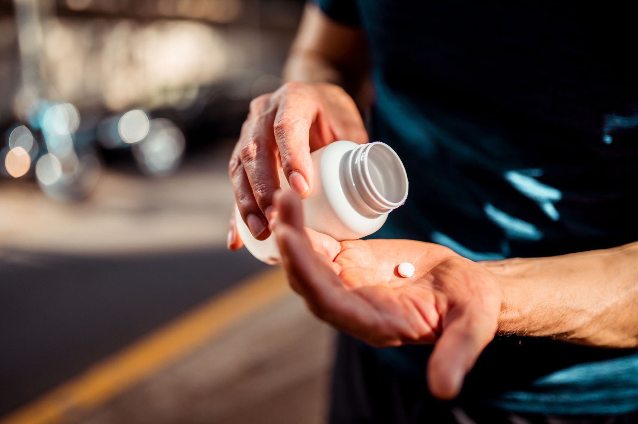 Close up of human hands. Man holding the medicine bottle in one hand and pill in other