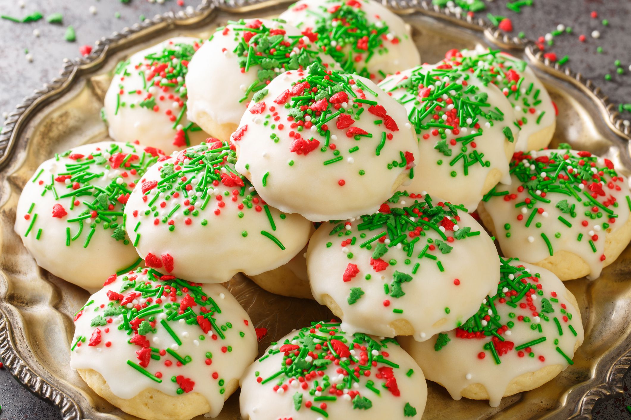 Italian Christmas Cookies a soft and sweet cake-like cookie covered with icing and sprinkles closeup in the plate on the table. Horizontal