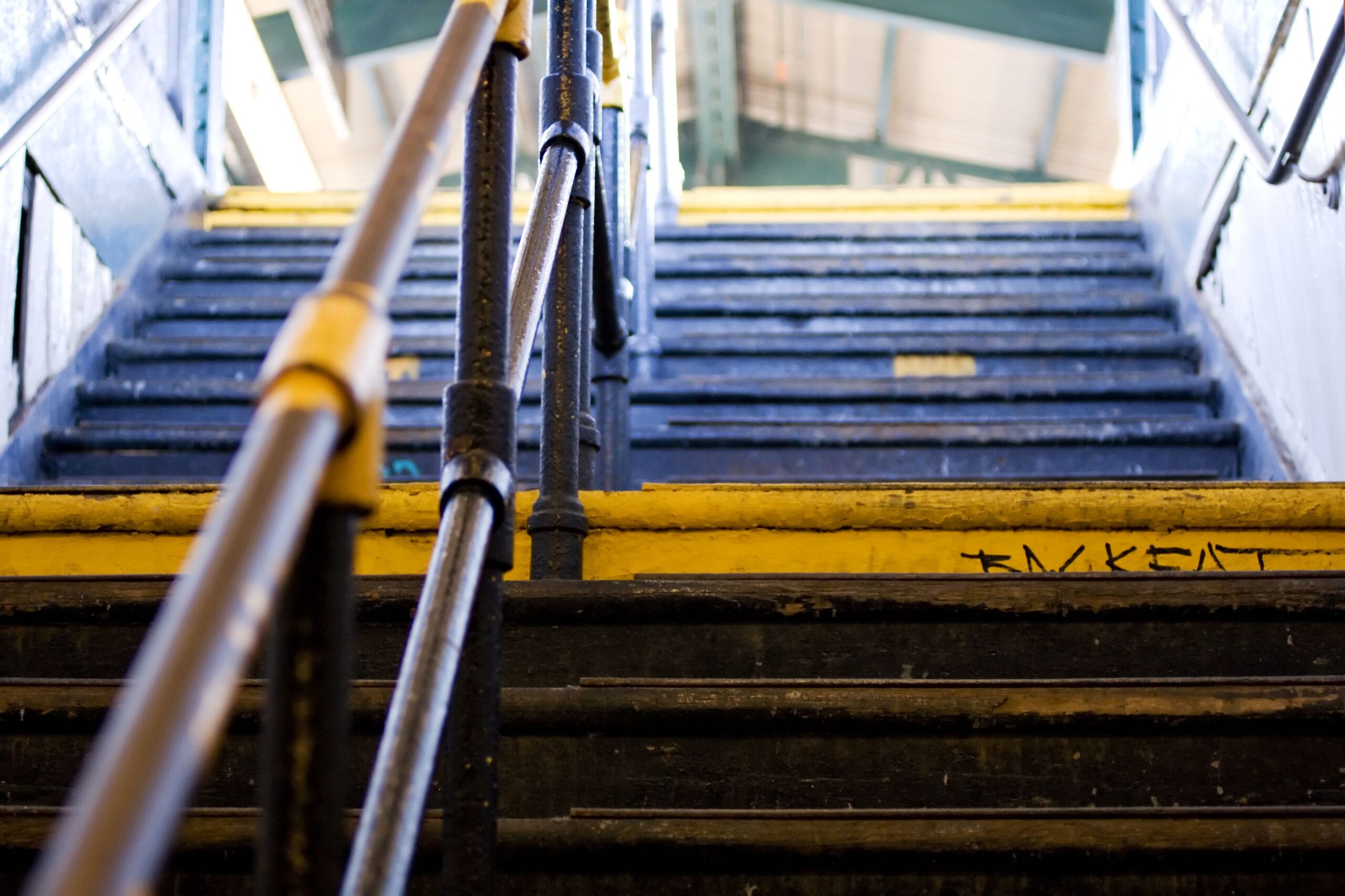 Railing and steps of a staircase leading to train platform on one of New York Subway stations.
