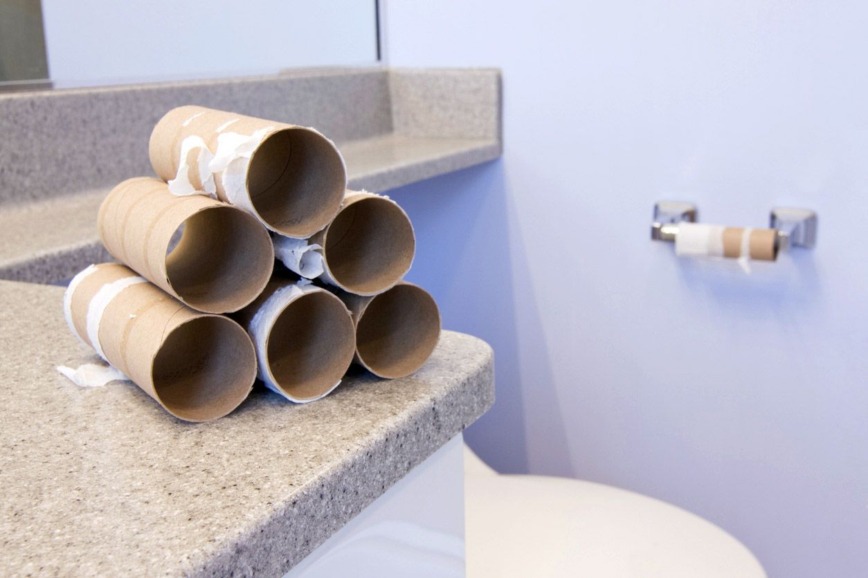 emptied toilet paper rolls on bathroom counter next to toilet
