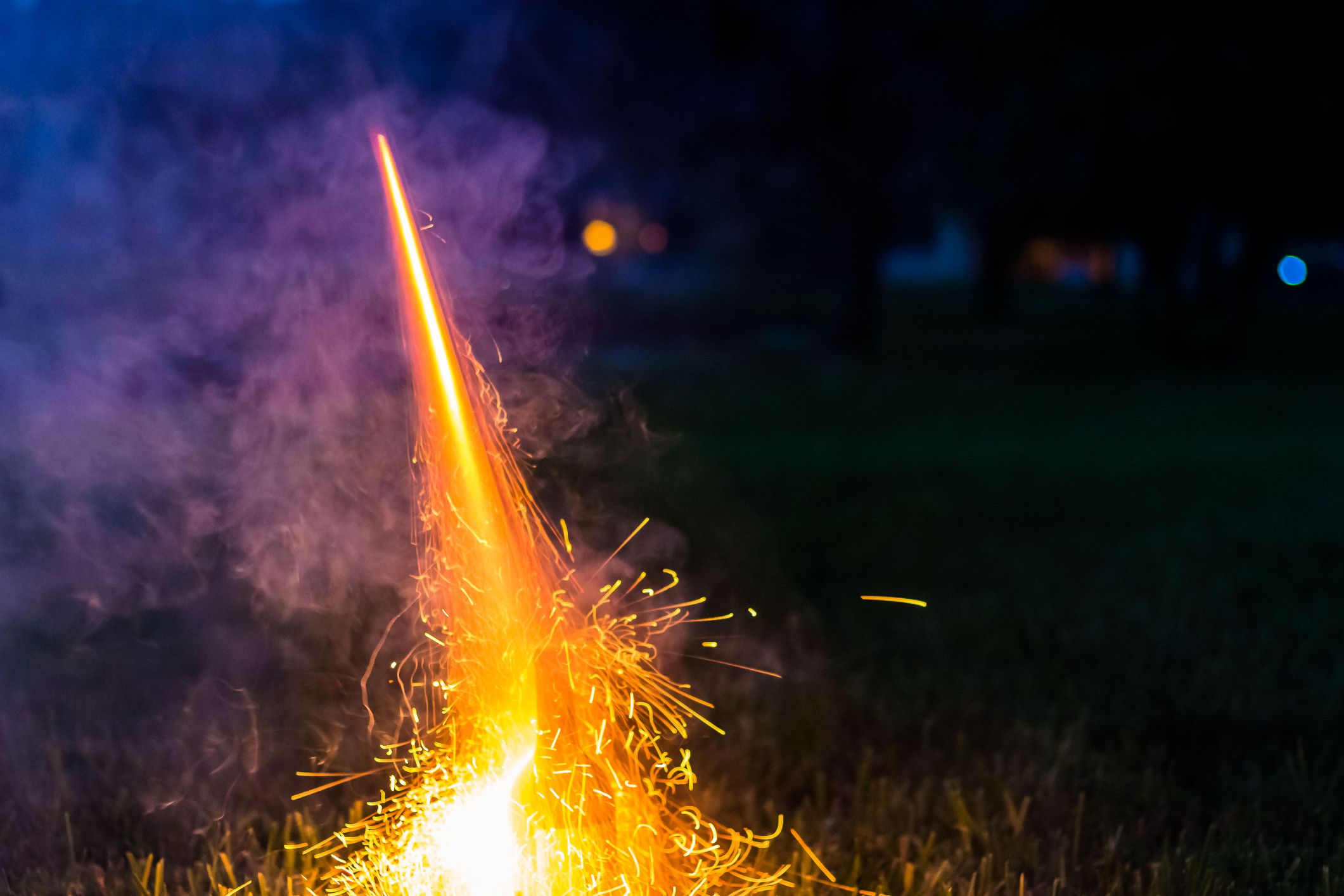 Lighting a bottle rocket out of a wine glass in the evening.