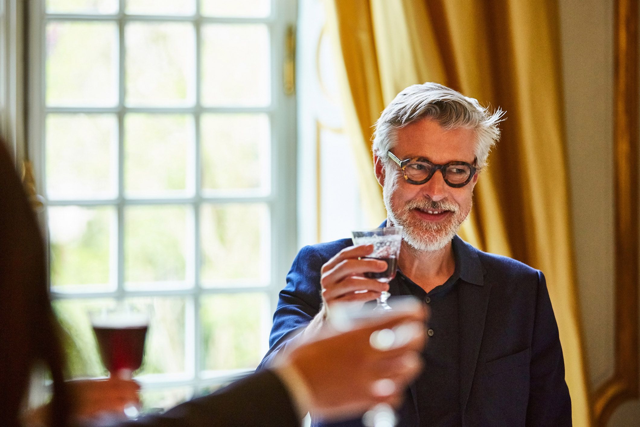 man sitting aside from rest looking off to his left and smiling