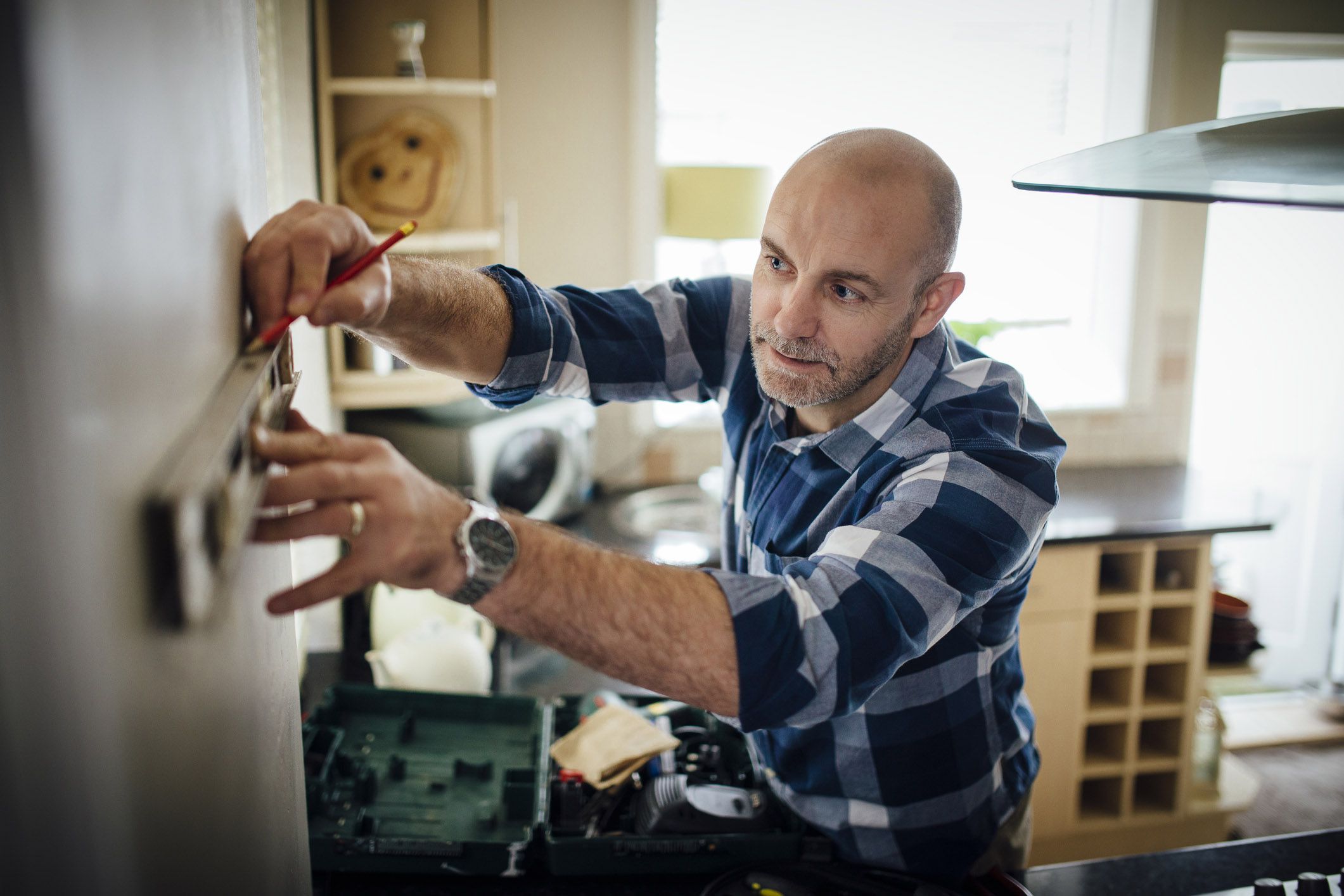 man with pencil measuring on wall to redecorate