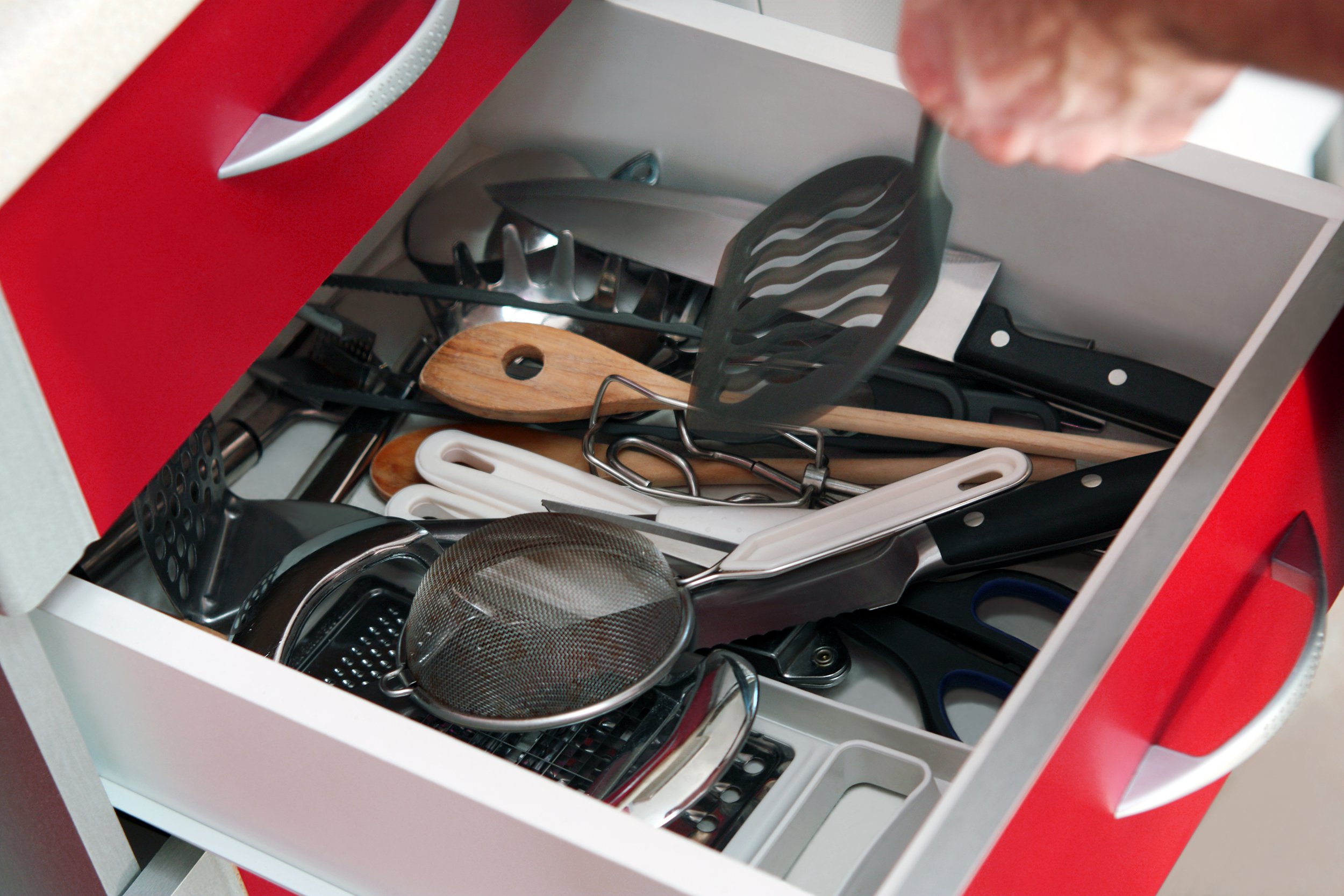 Messy kitchen drawer with utensils unorganized