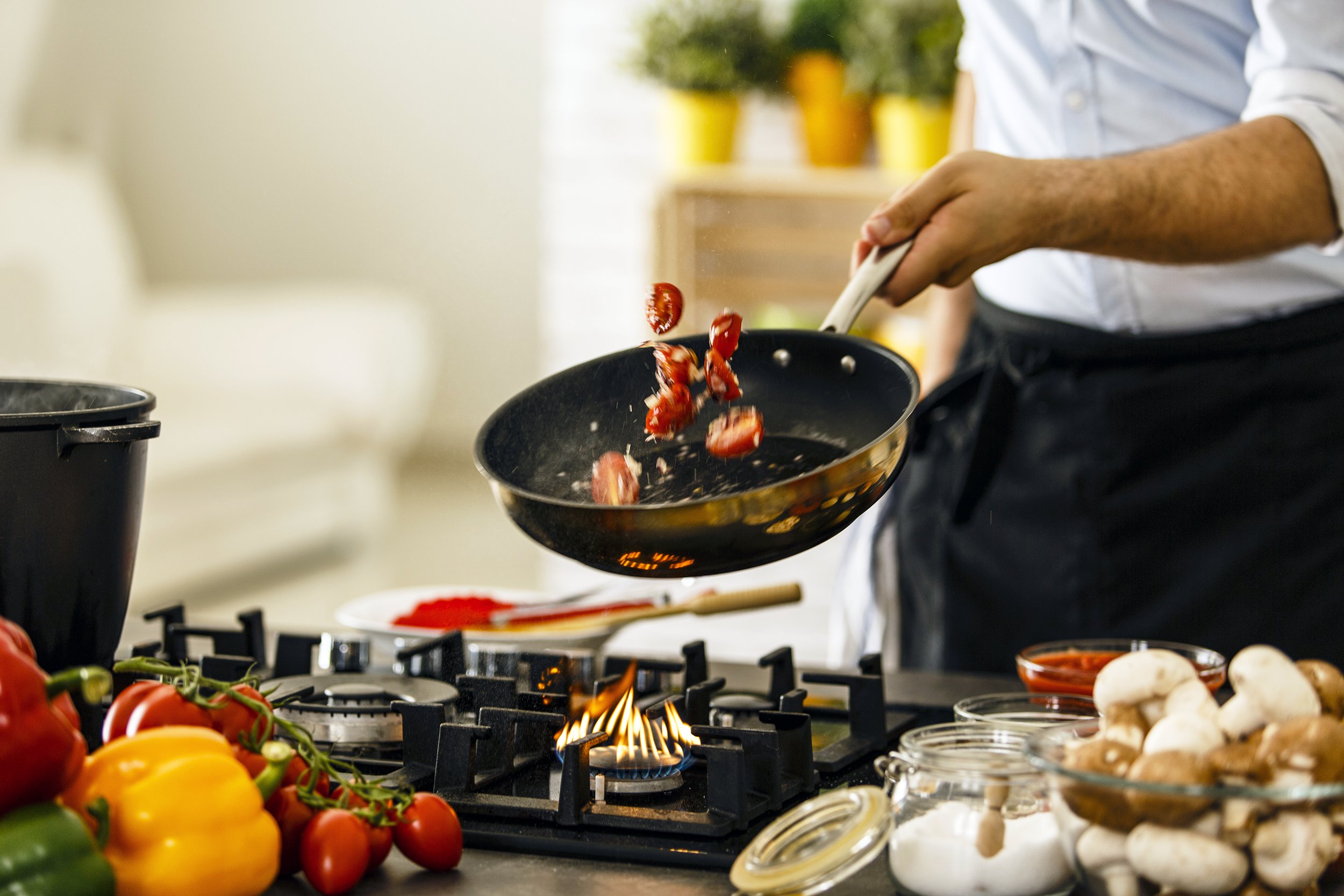 Man flipping vegetables in a saute pan