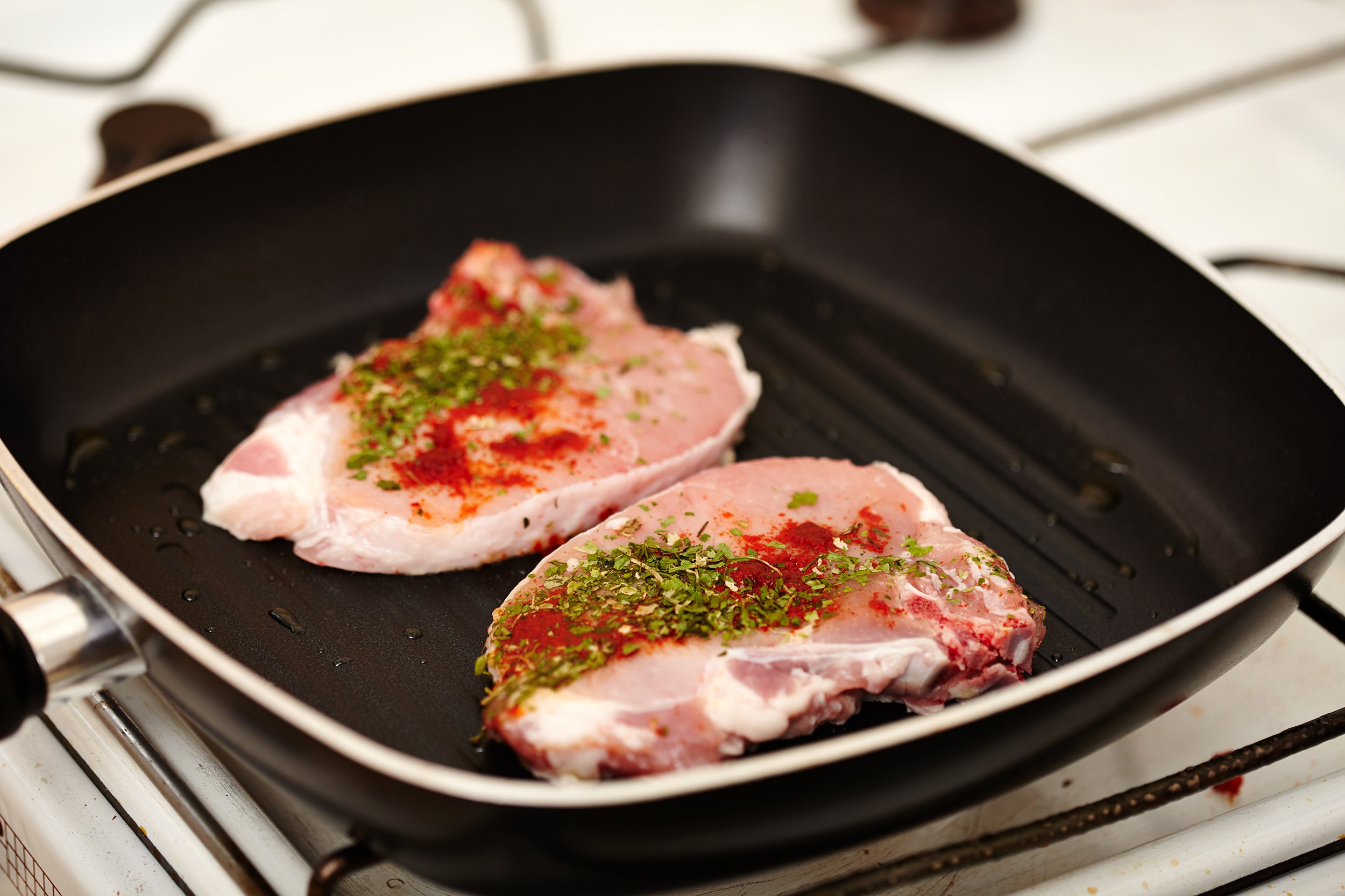 Seasoned pork chops sitting in a cold pan
