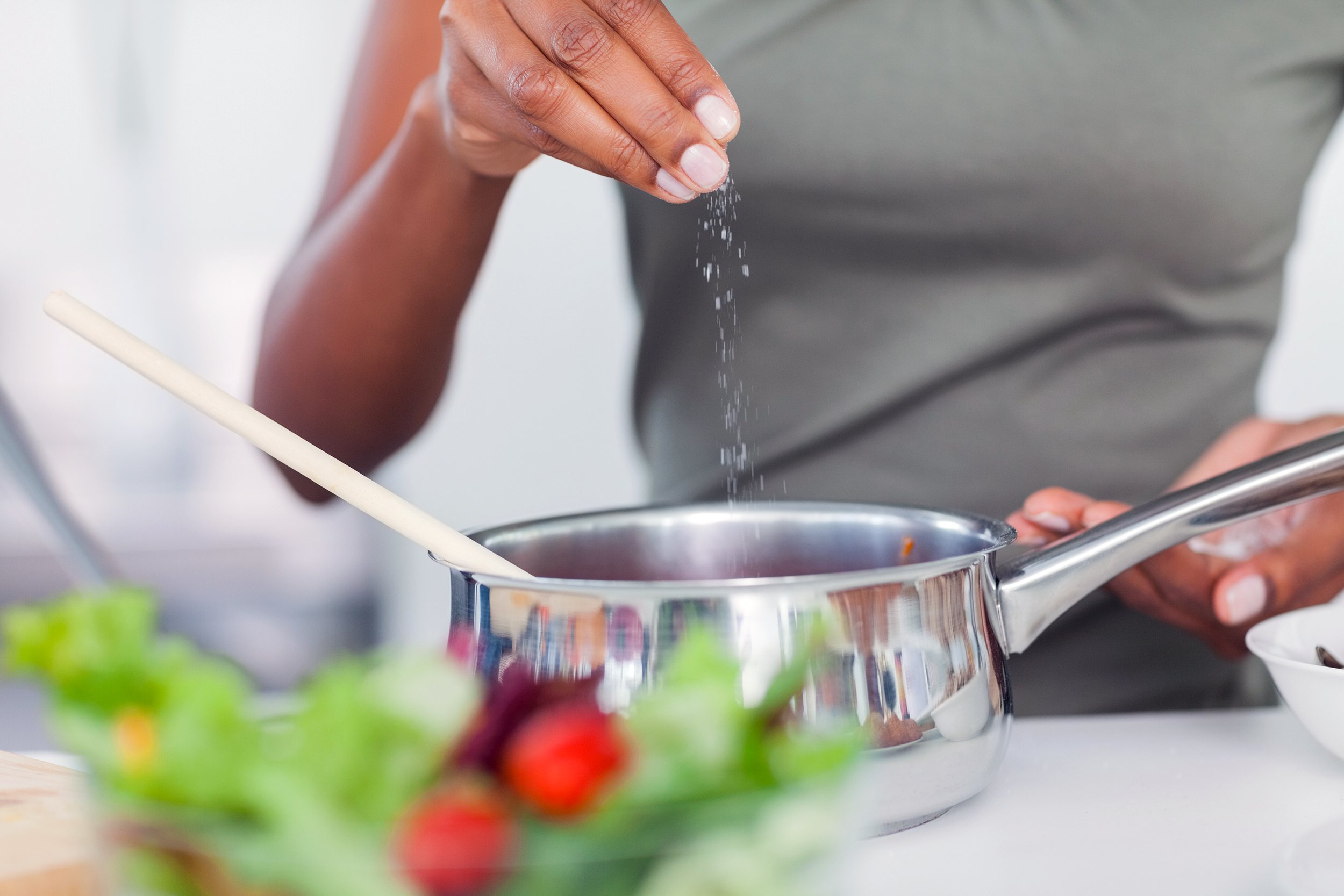 Woman seasoning her dish while cooking