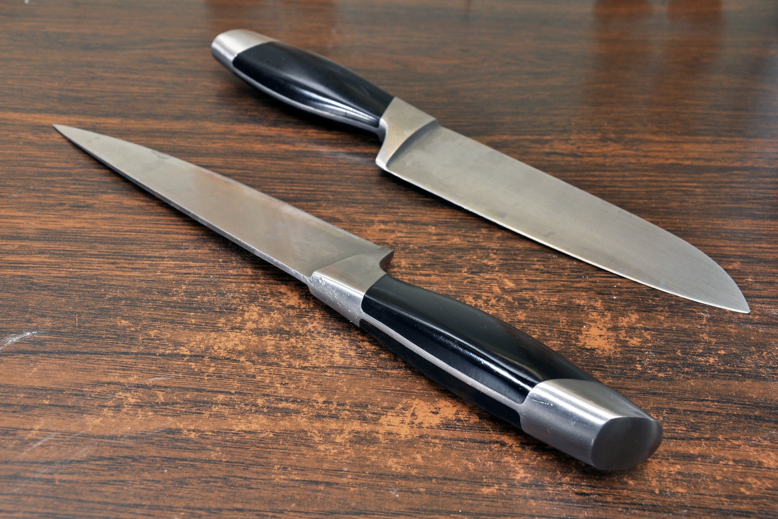 Two knives on a wooden counter