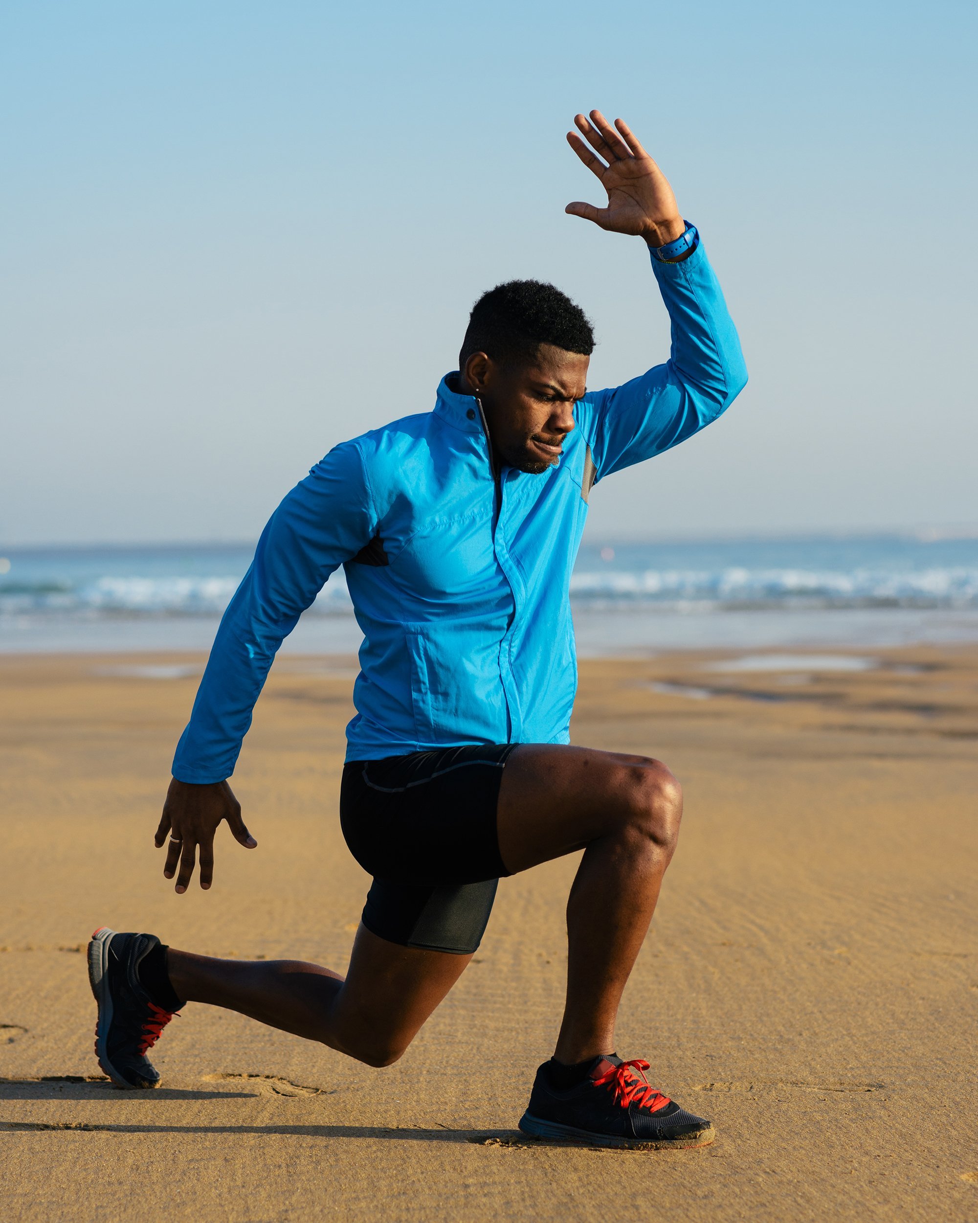 man doing walking lunges on the beach
