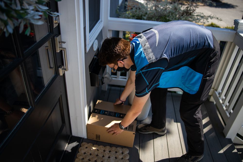 Amazon delivery person with package at door