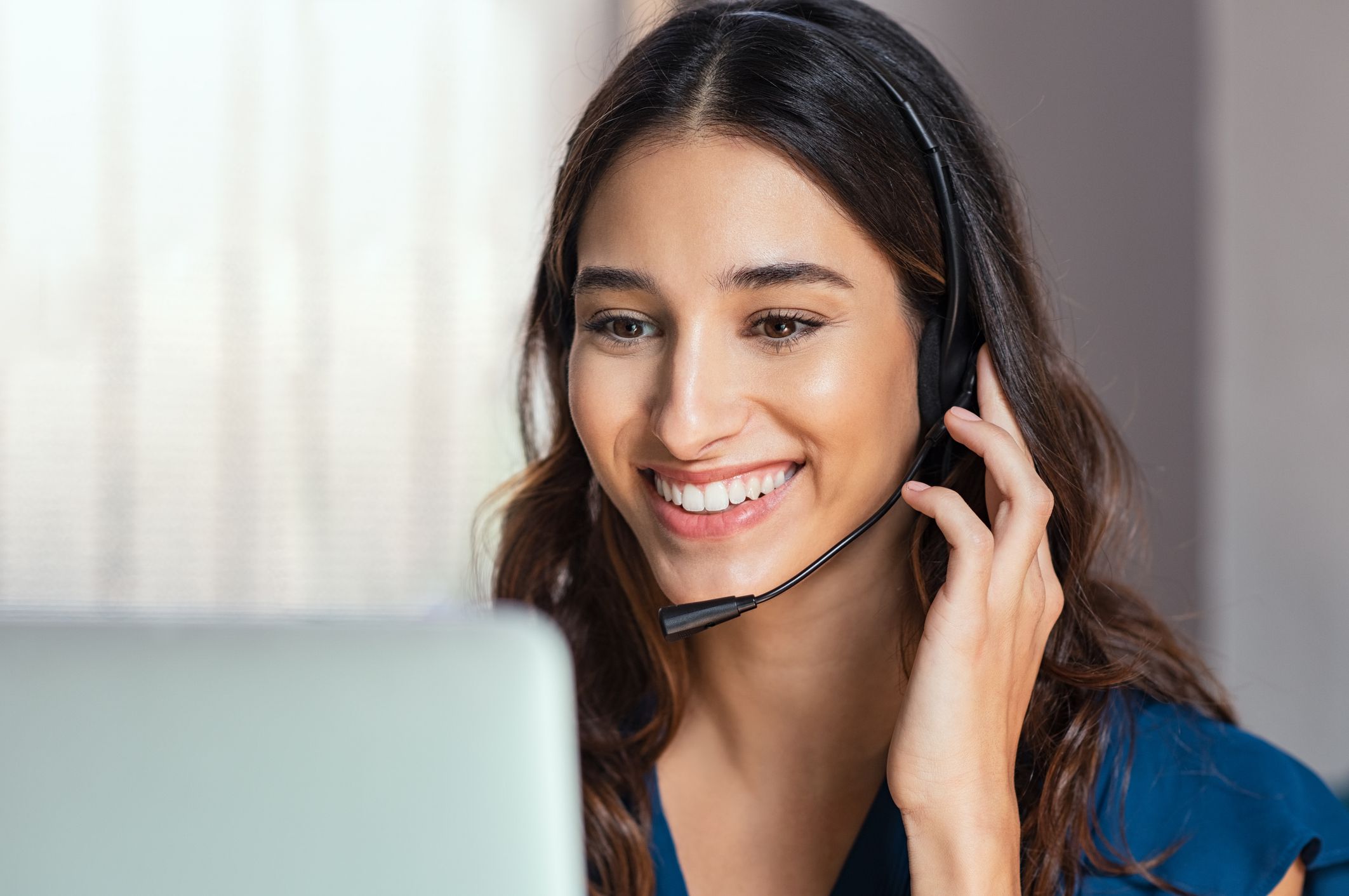 Closeup of female telemarketer with blurred back of computer screen