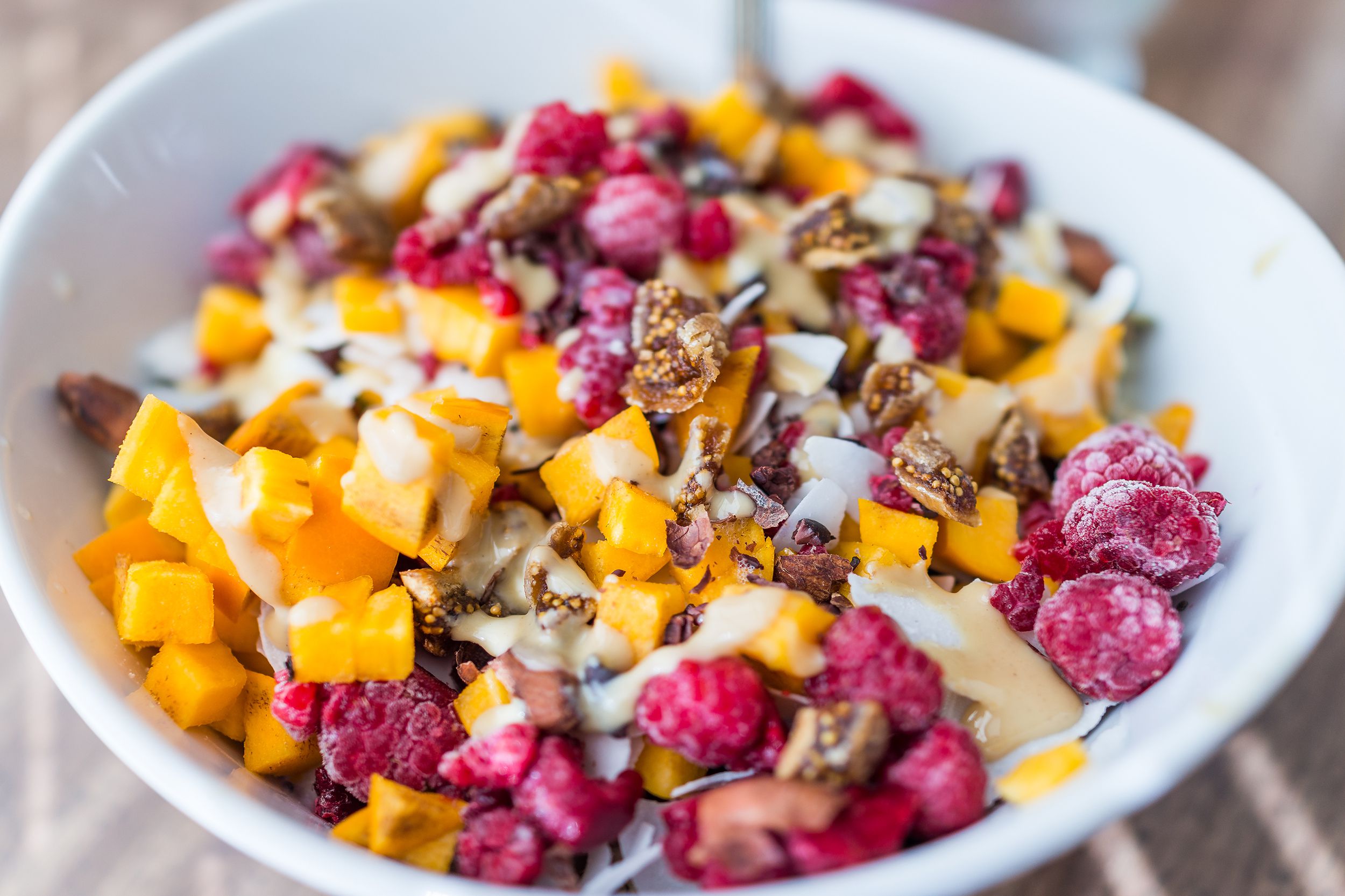 Fresh fruit with applesauce-sweetened tahini in a white bowl with a blurred background