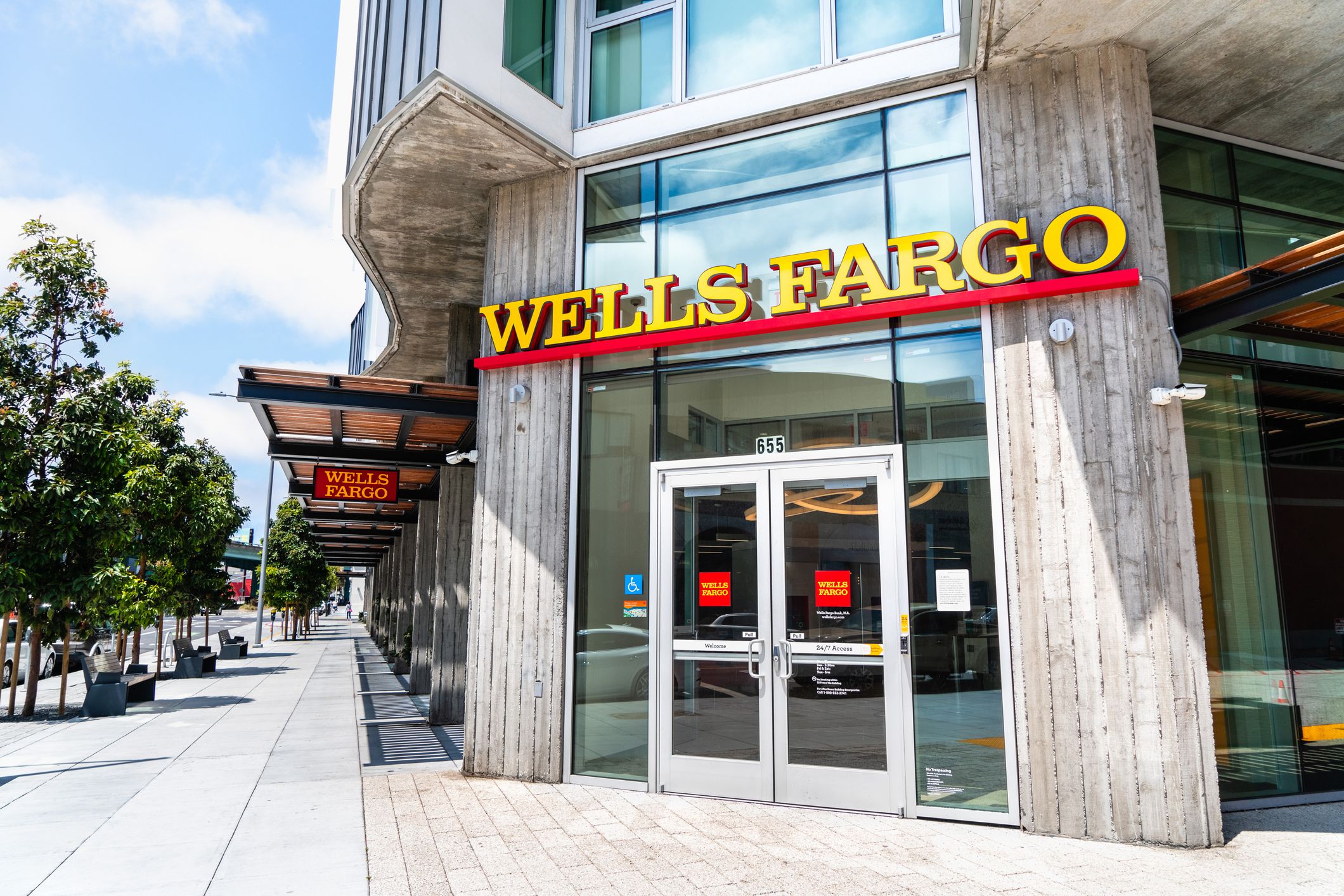 Front exterior Wells Fargo branch in the SOMA District of San Francisco, focus on doors, with tree-lined sidewalk to the left