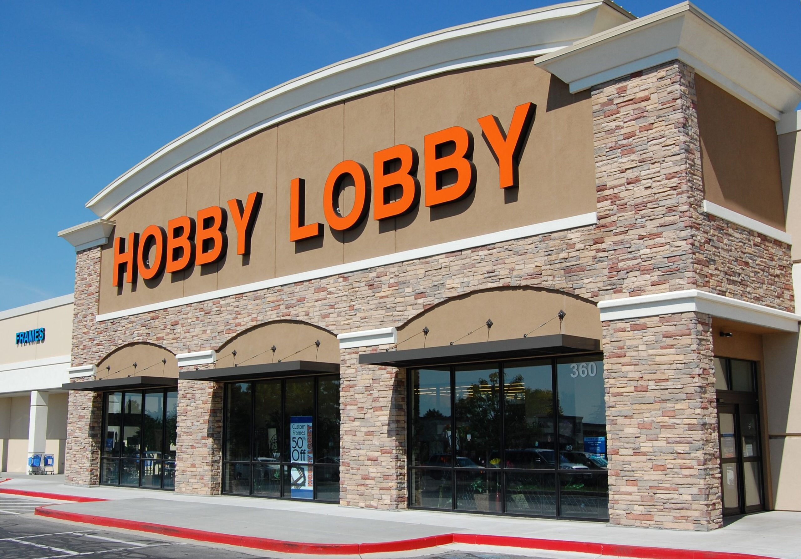 Front exterior of Hobby Lobby Retail Store, Orem, Utah, sidewalk in the foreground with a clear blue sky in the background
