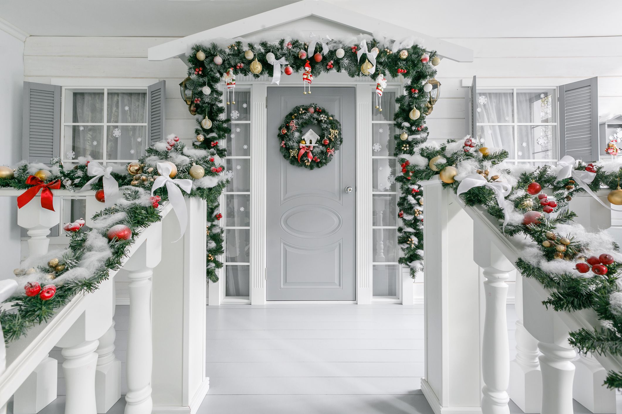 Front porch with front door and windows decked with Christmas decorations, as seen from top stair, white and light grey colors