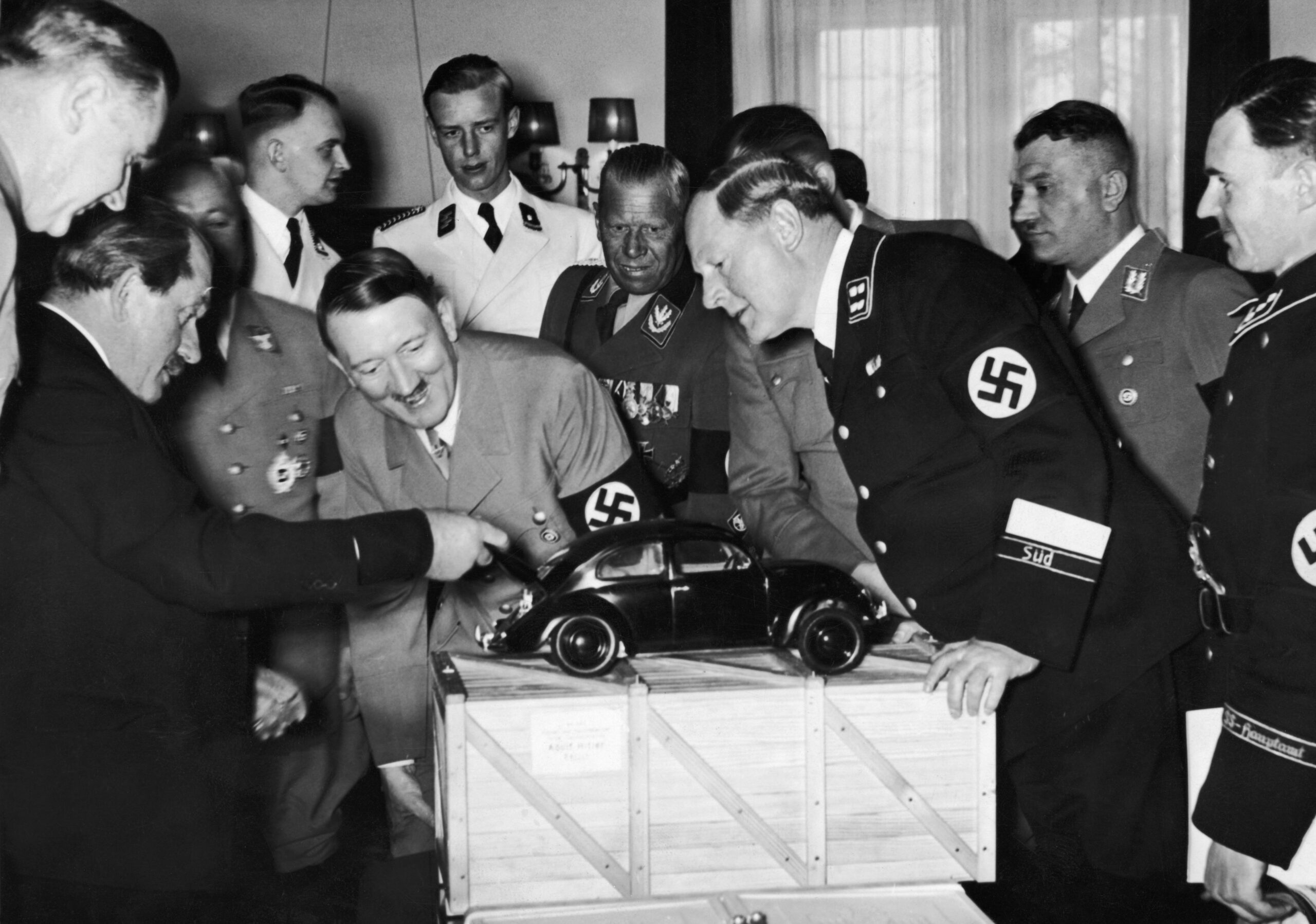 Adolf Hitler (1889 - 1945), the German Dictator admires a model of the Volkswagen car and is amused to find the engine in the boot.