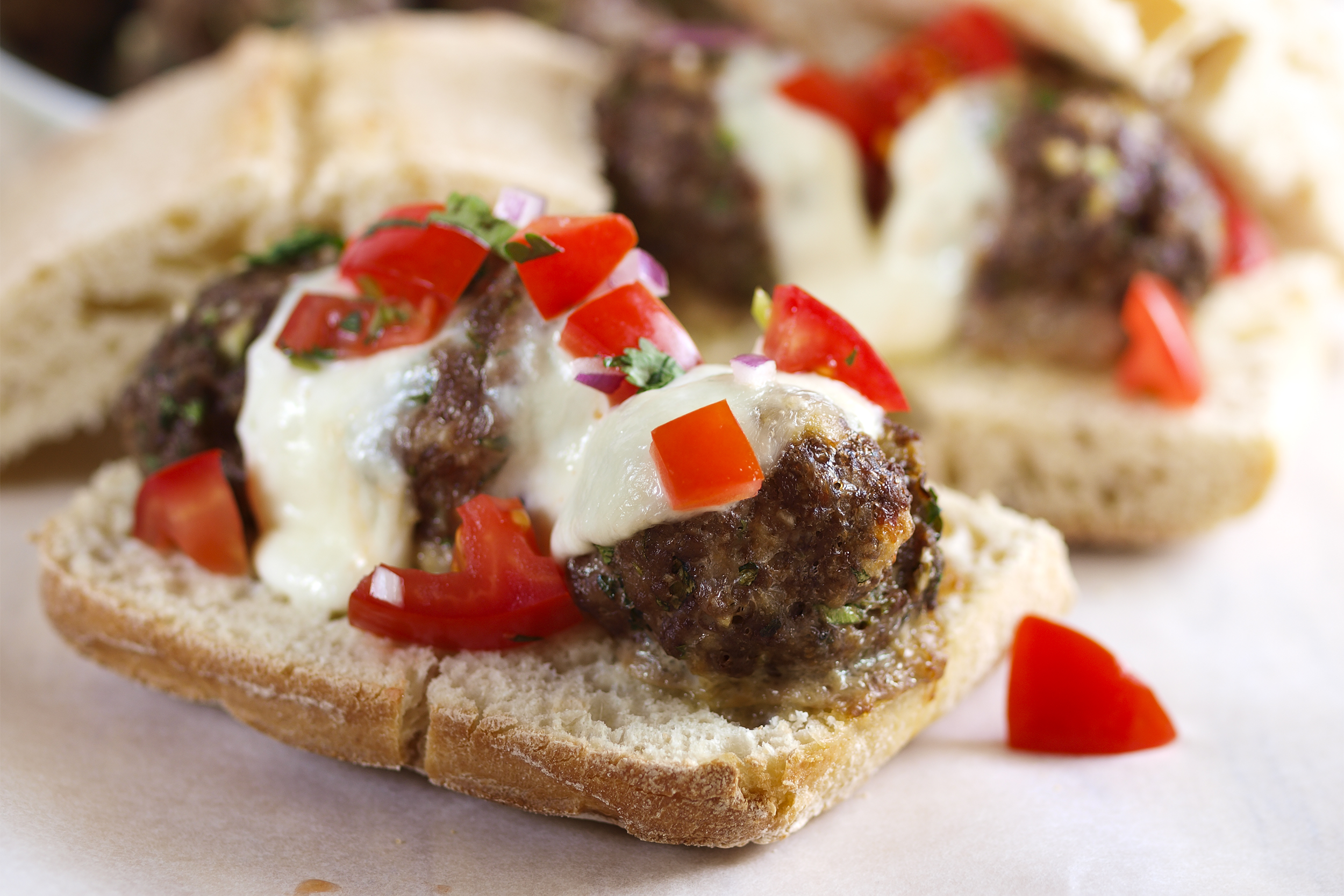 Meatball sandwich with cheese and diced tomato