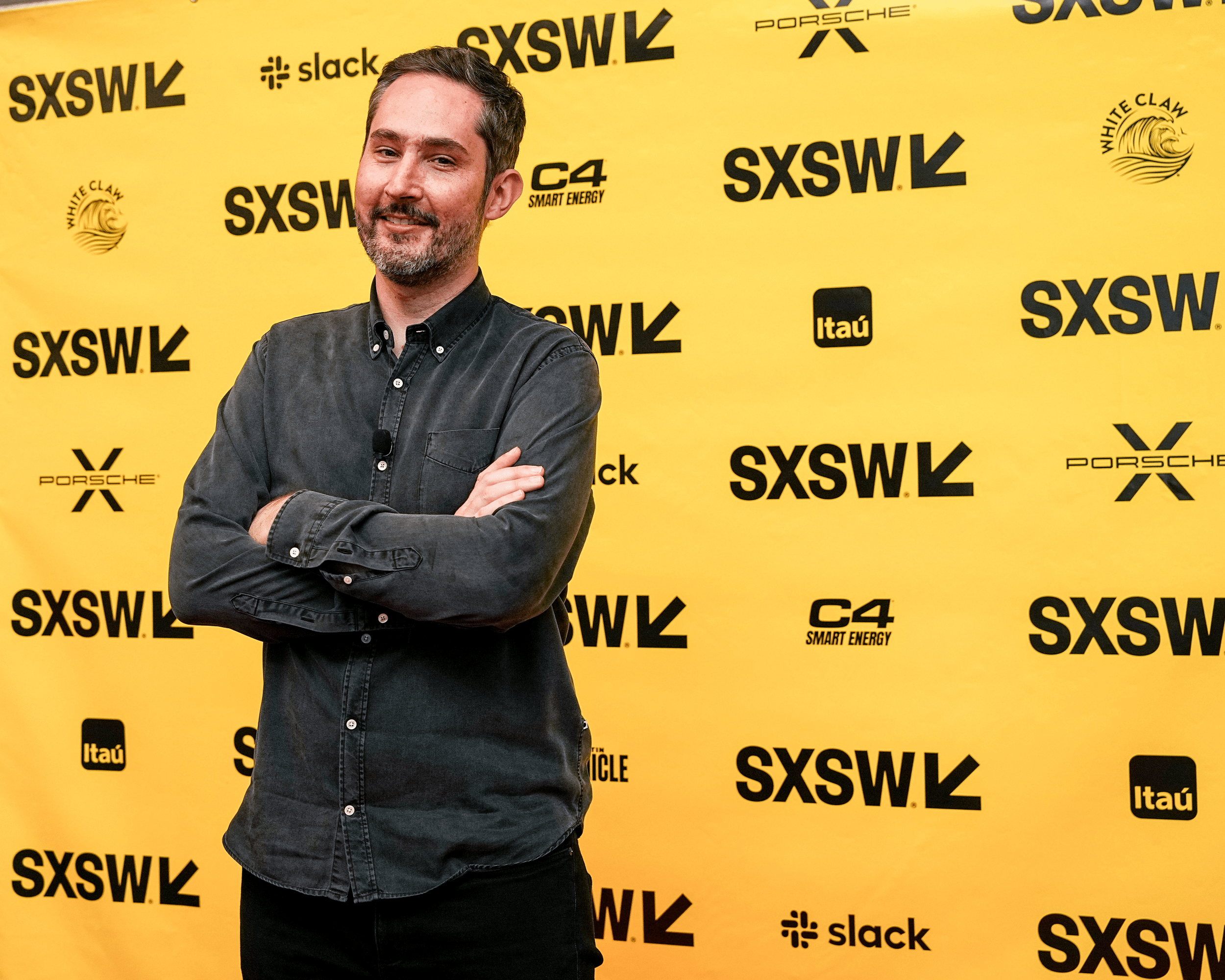 Kevin Systrom smiles with arms crossed, attends the 2023 SXSW Conference and Festivals at the Austin Convention Center, Austin, Texas, 2023, black logos on a yellow background