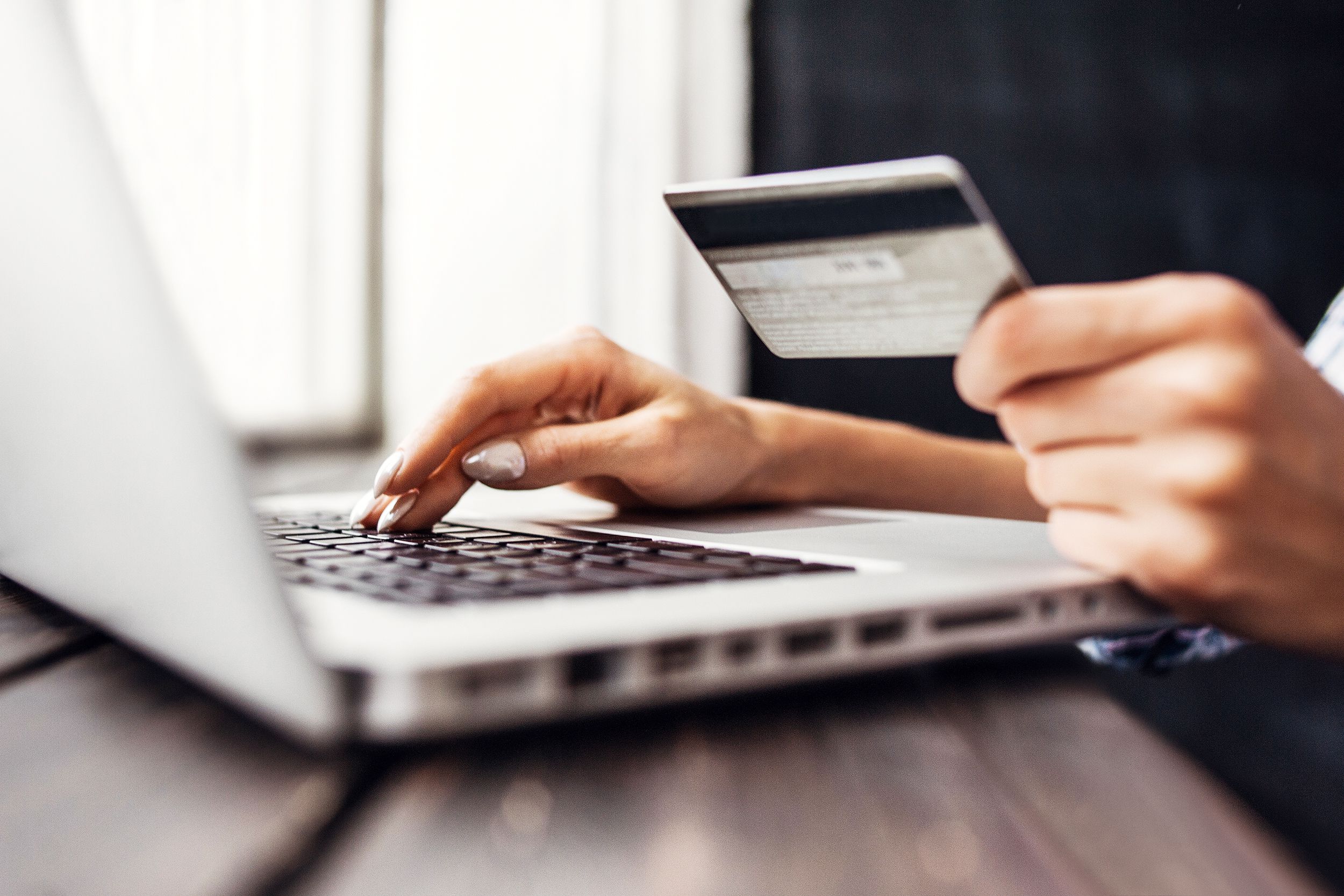 Closeup of laptop and hands holding a credit card