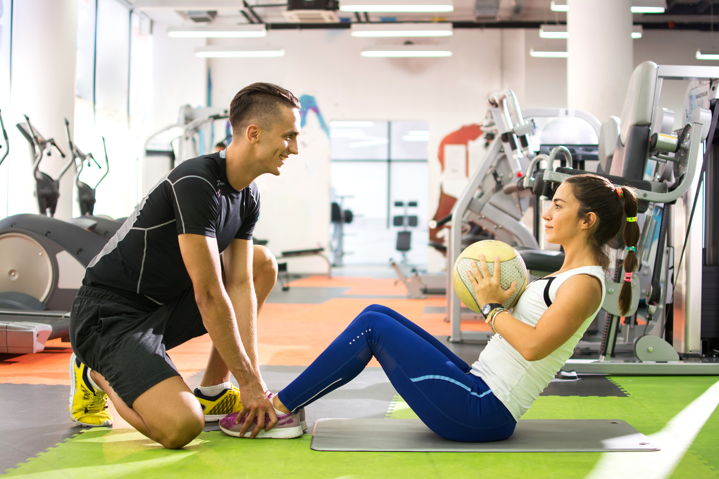 Personal trainer holding feet while a woman does sit ups