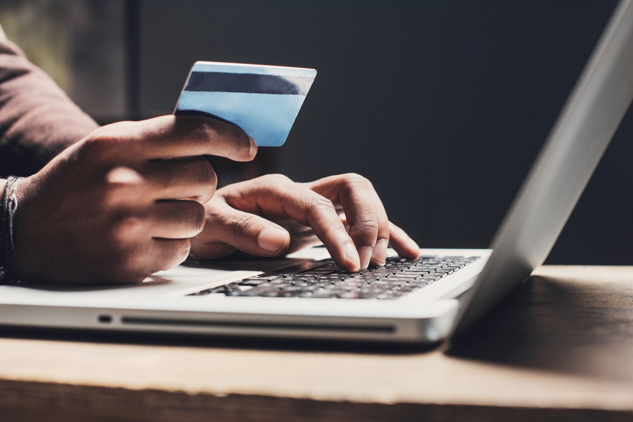hands entering credit card information using laptop computer keyboard