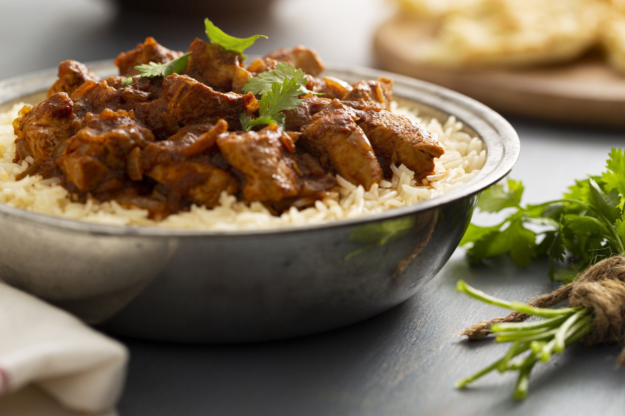 Indian Food - Bowl of chicken vindaloo curry over basmati rice and naan bread.