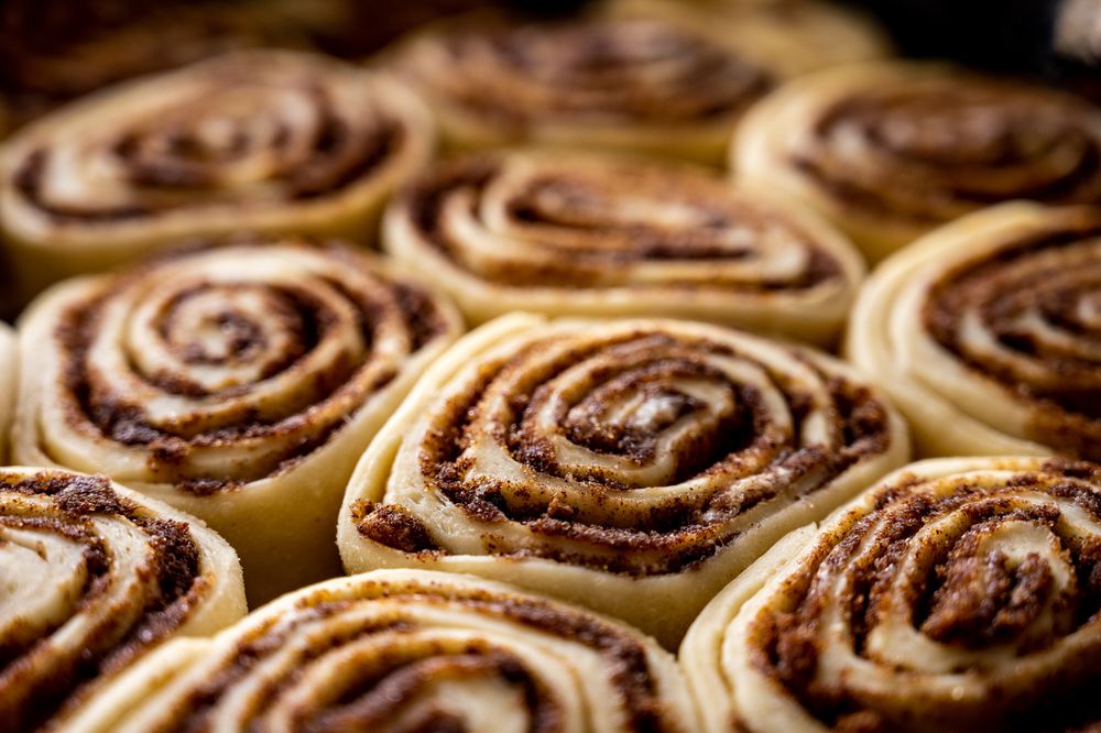 Close-up of several unbaked cinnamon rolls arranged closely together, showing swirled layers of dough and cinnamon filling.