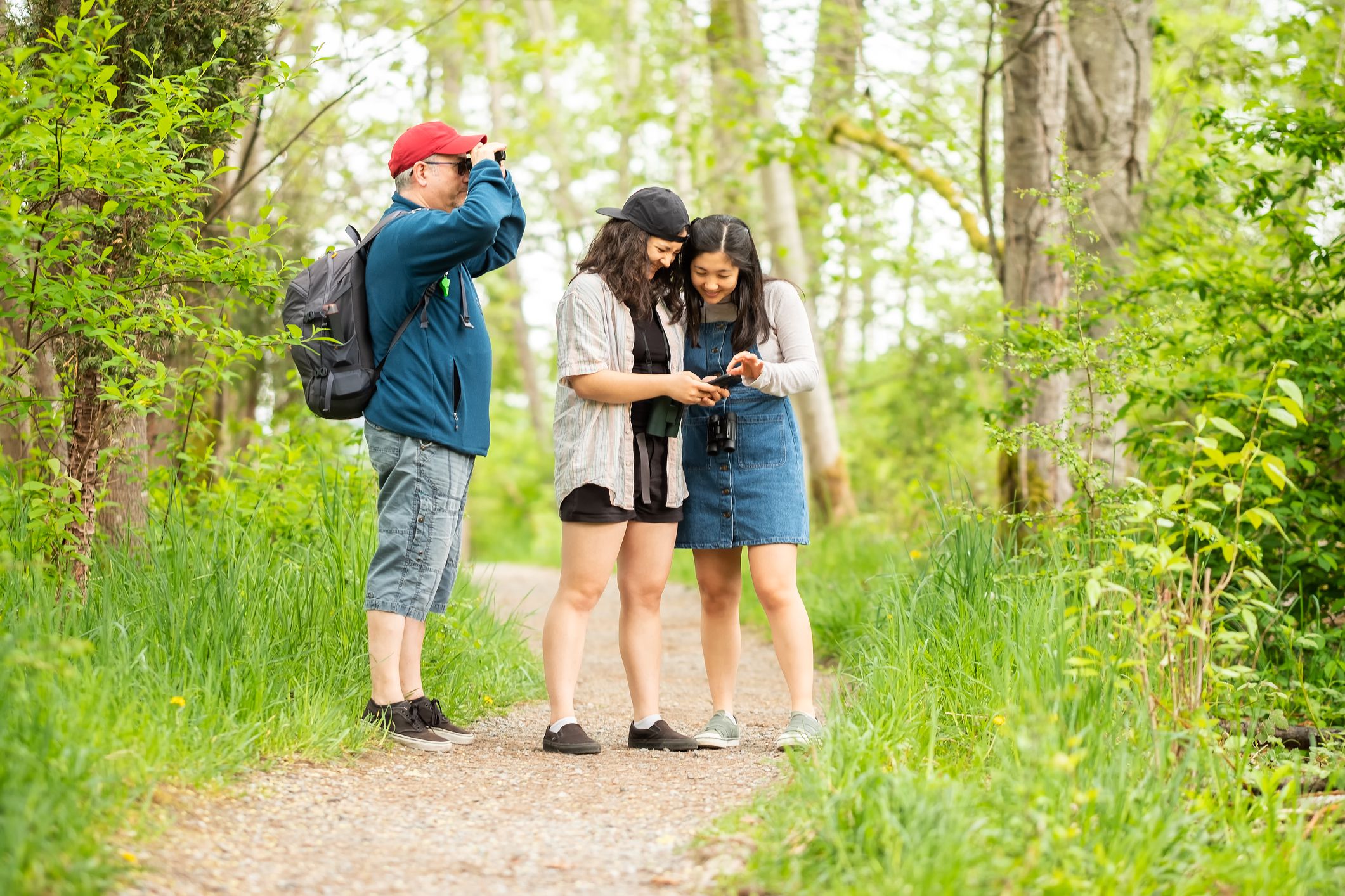 Multi-racial, 2 generation family birdwatching in forest. North Vancouver, British Columbia, Canada