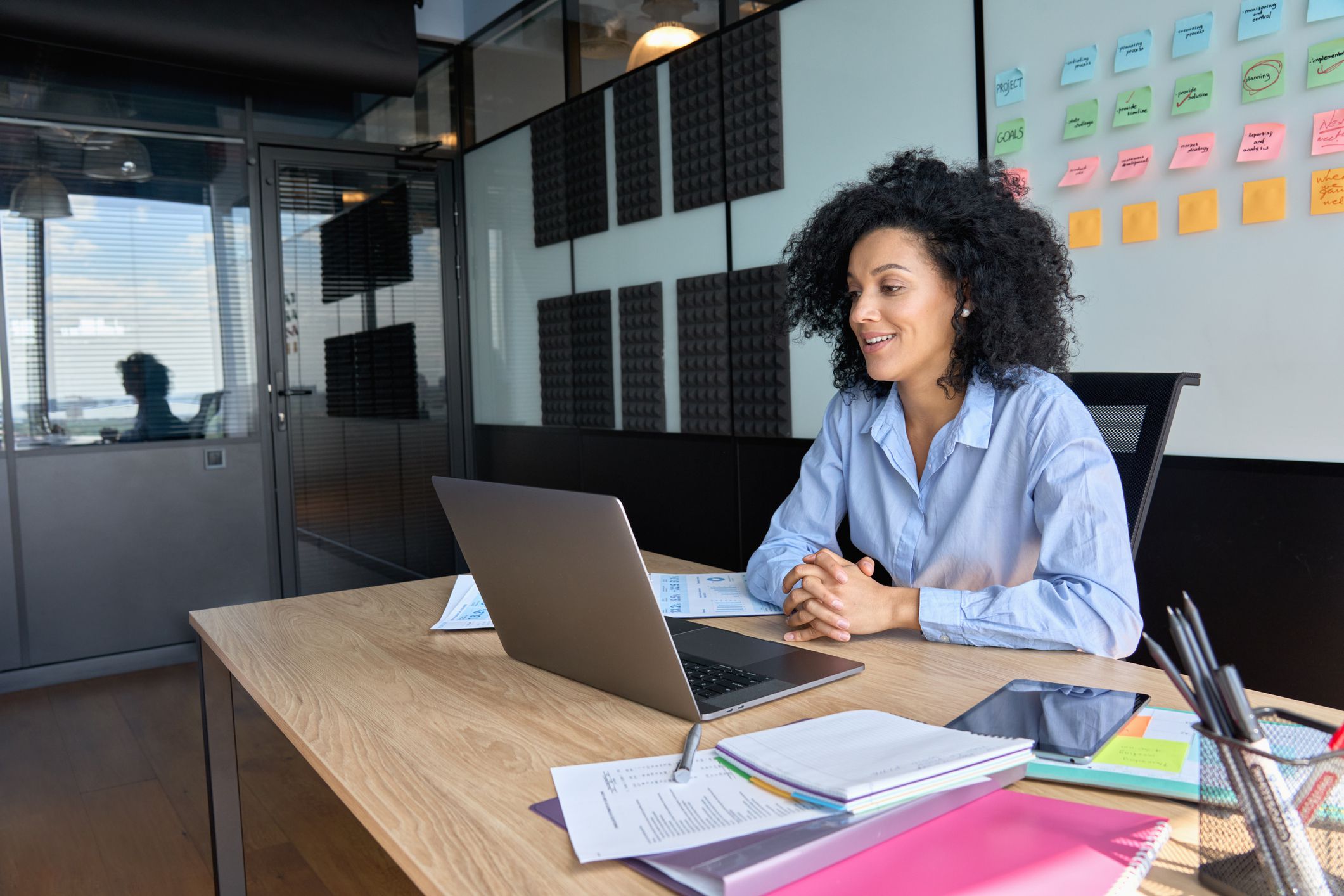 Successful African American businesswoman sitting at desk having working videoconference on yearly global financial report with client using laptop computer in contemporary corporation office.