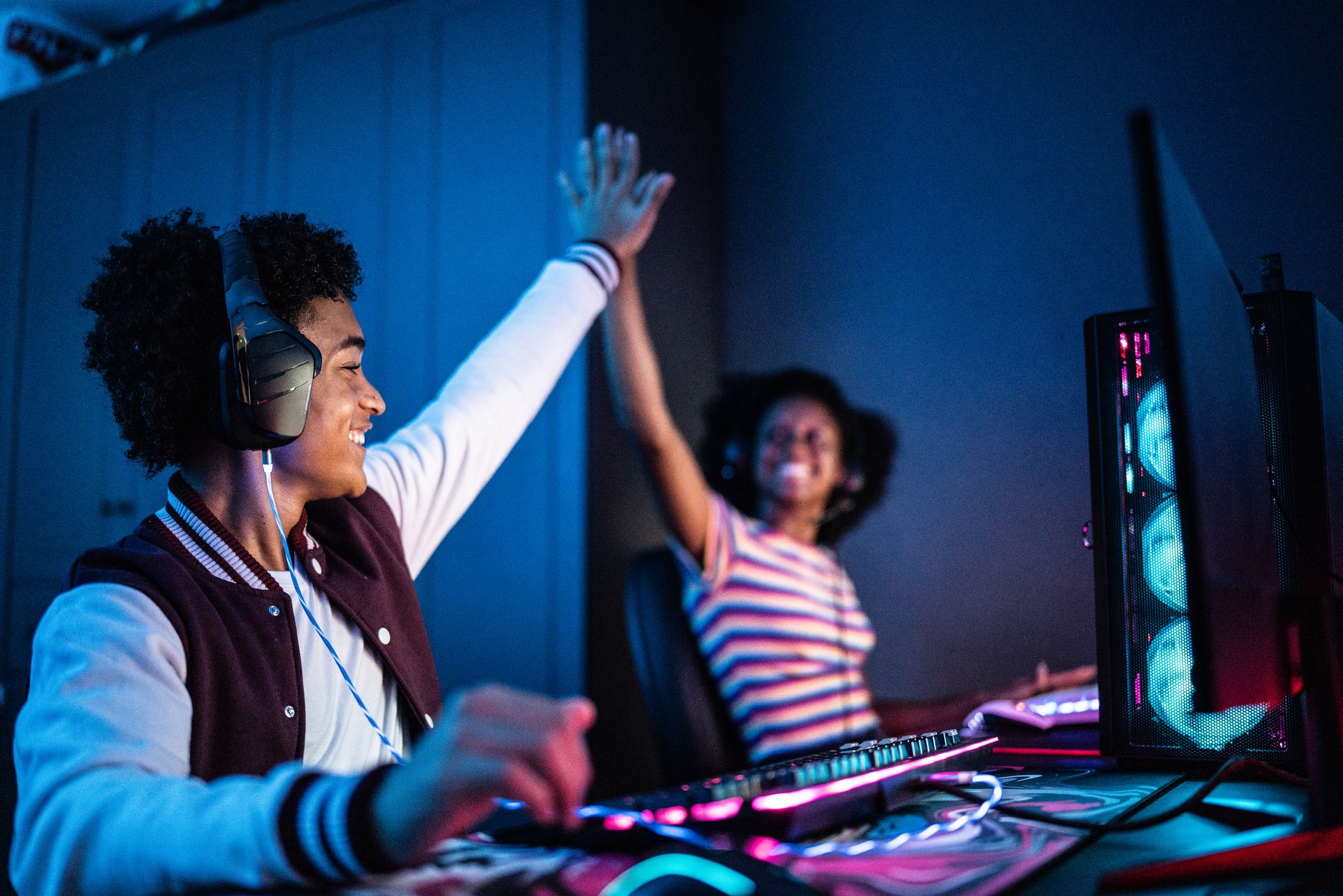 Friends doing a high five while playing on the computer at home