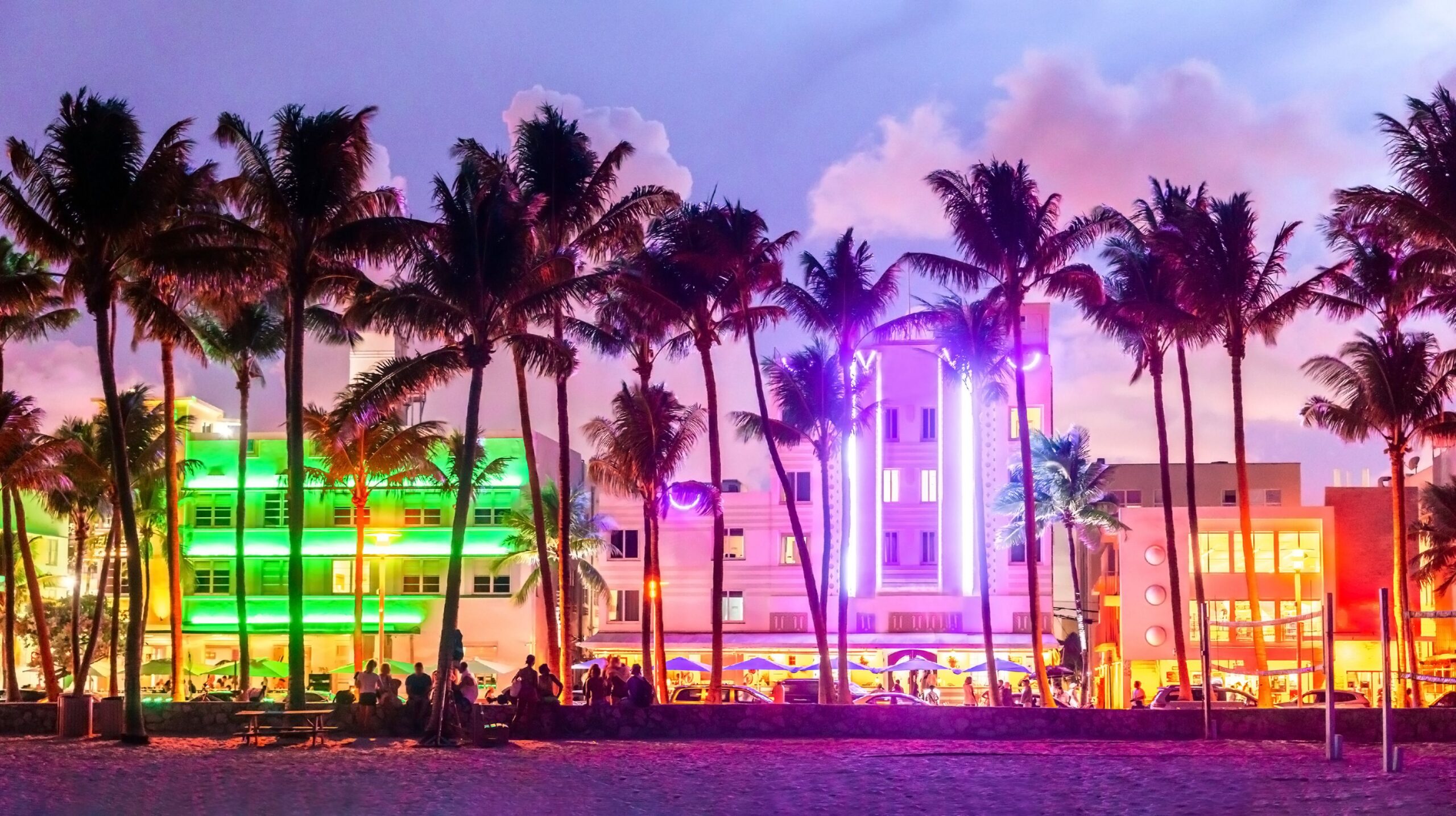 Miami Beach Ocean Drive hotels and restaurants at sunset. City skyline with palm trees at night. Art deco nightlife on the South beach