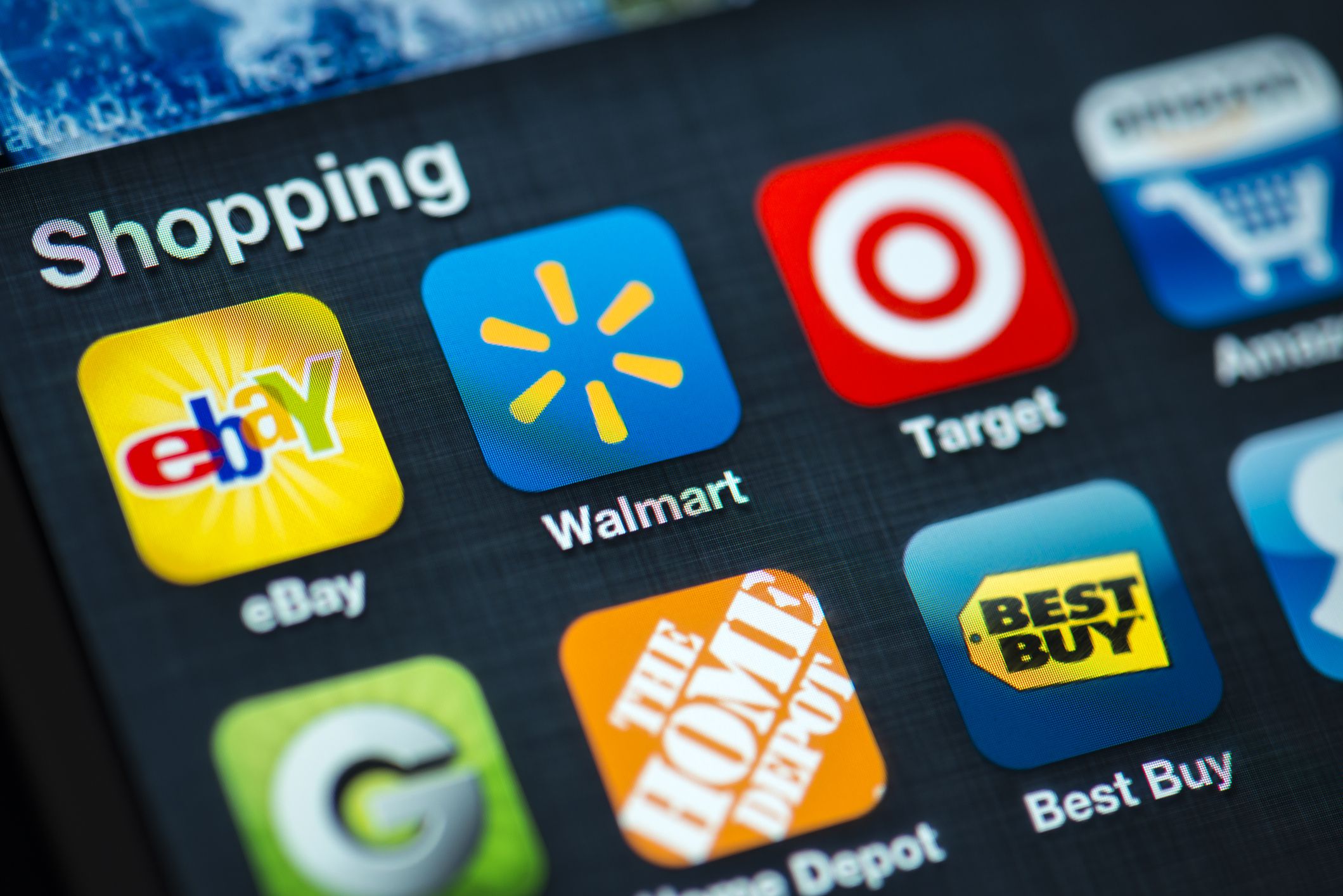 A close up of an Apple iPhone 4s screen showing various Shopping apps, including eBay, Walmart, Target, Amazon, Groupon, Home Depot, Best Buy