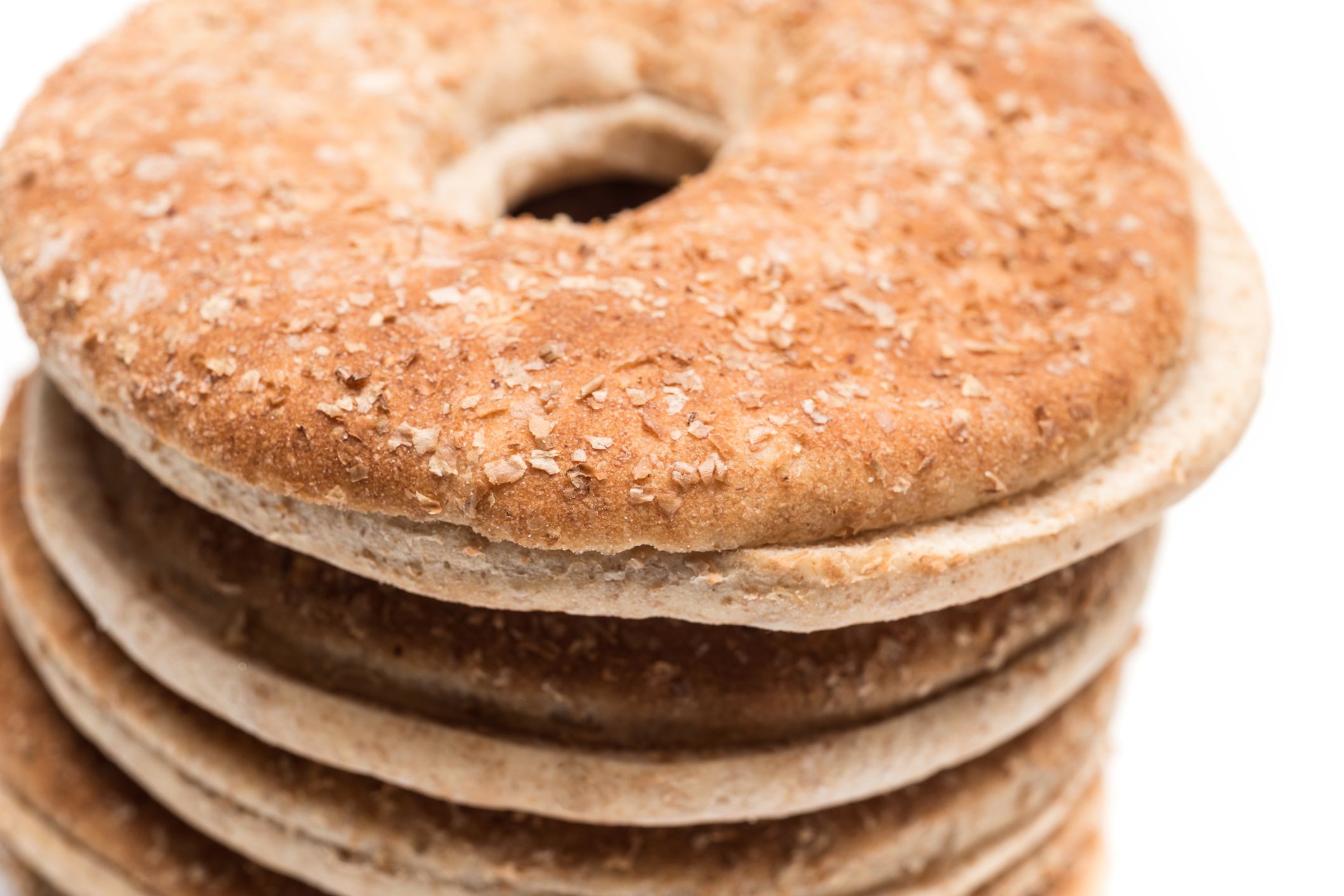 A close-up of a stack of round, flat, whole grain crispbreads with a hole in the center, against a white background.