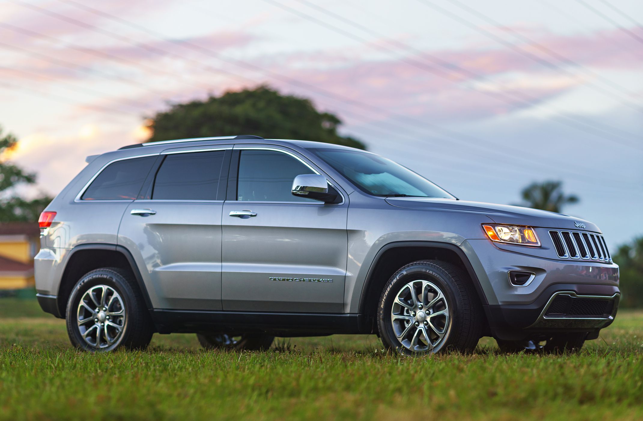 Miami, USA - February 6, 2014: Metallic Silver Jeep Grand Cherokee 4x2 2014 SUV parked outside in a suburban grass field in the afternoon.