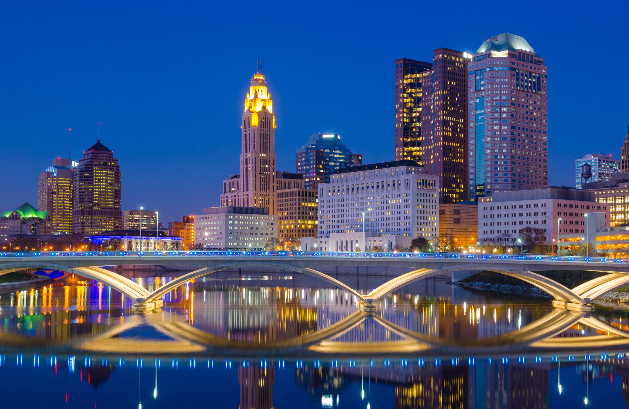 Downtown Columbus skyline at late dusk / early evening with a partial skyline reflection off of the Scioto River.