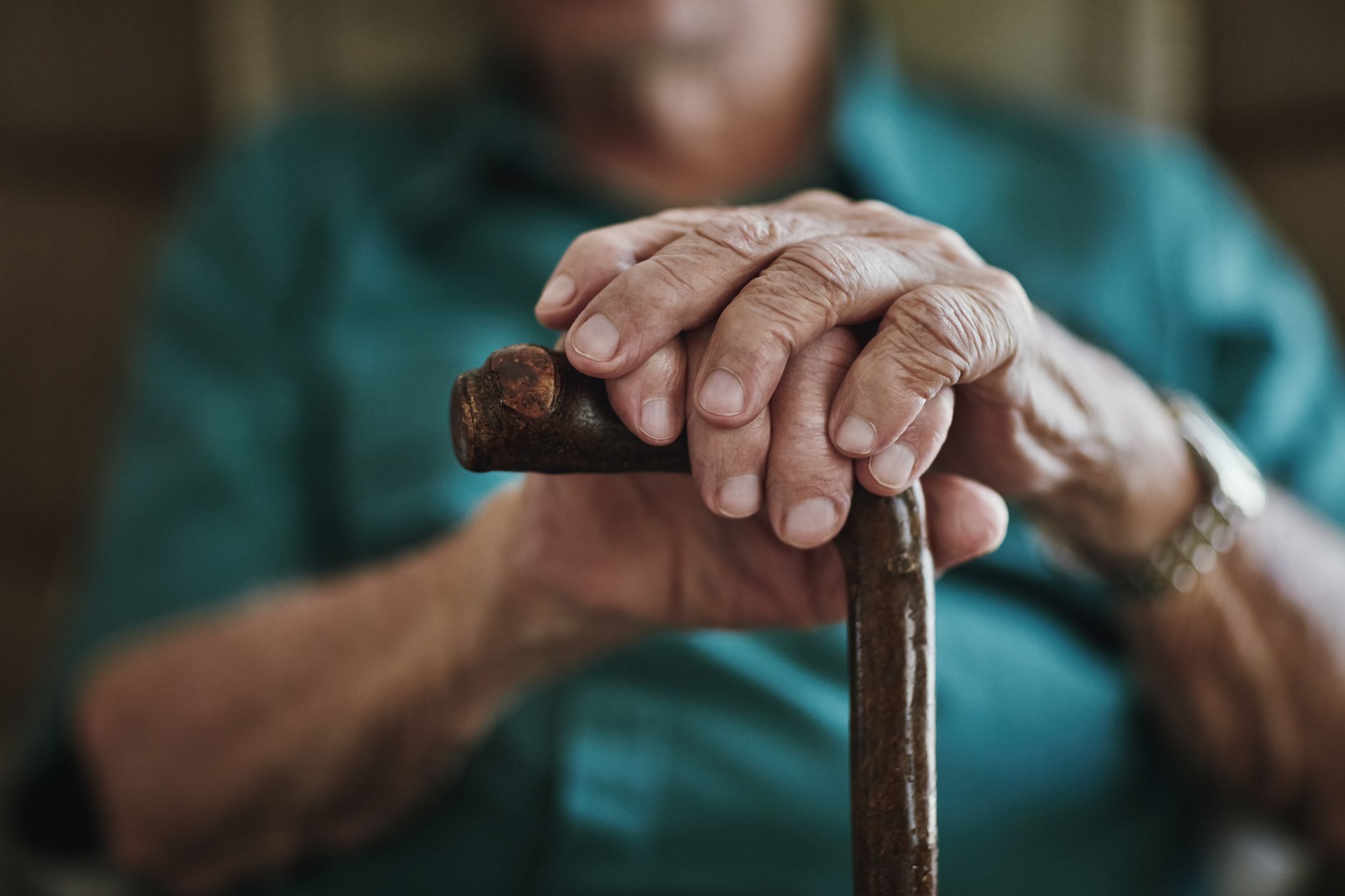 Cropped shot of an unrecognizable man leaning on his walking stick