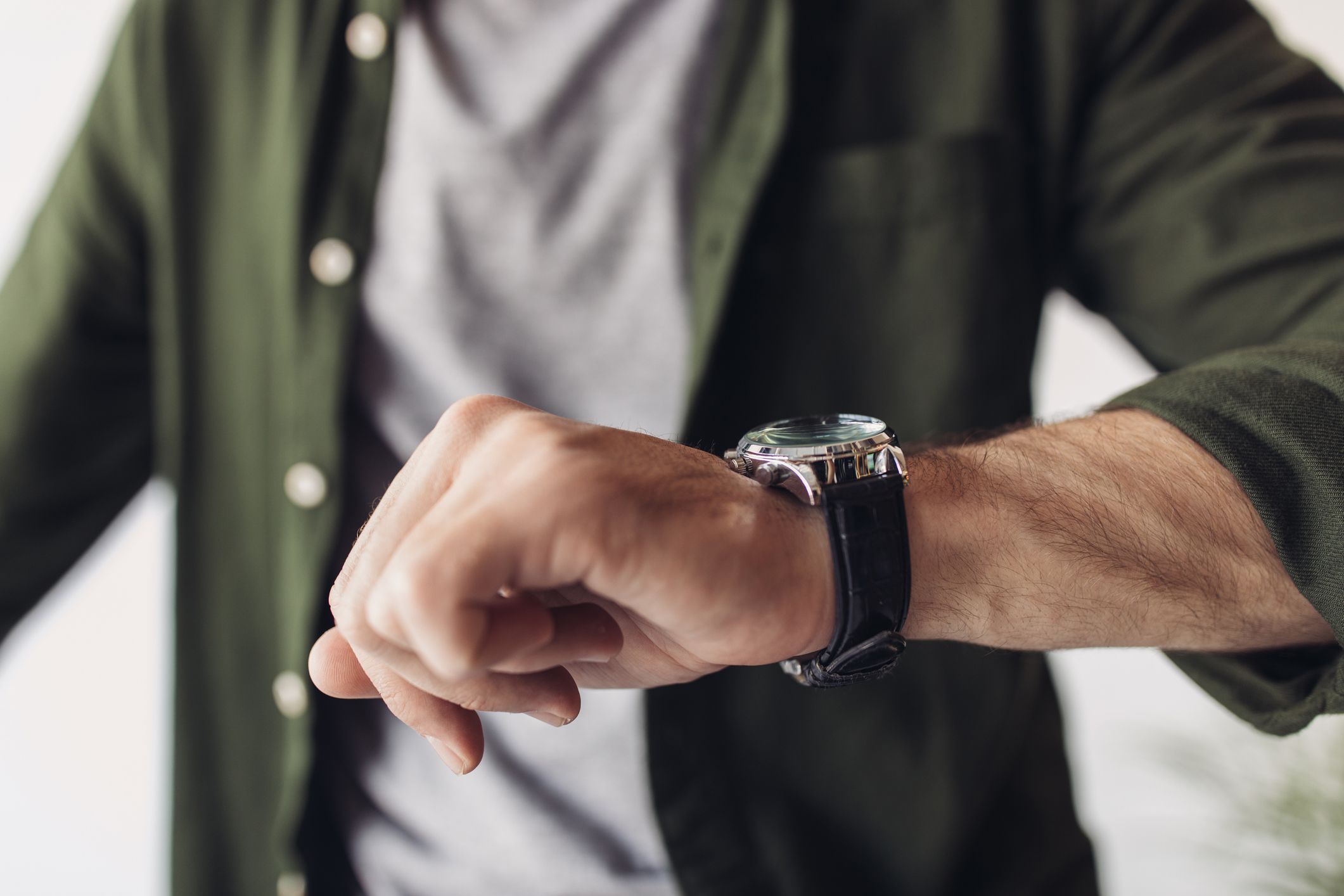 Cropped shot of man in shirt checking wristwatch indoors